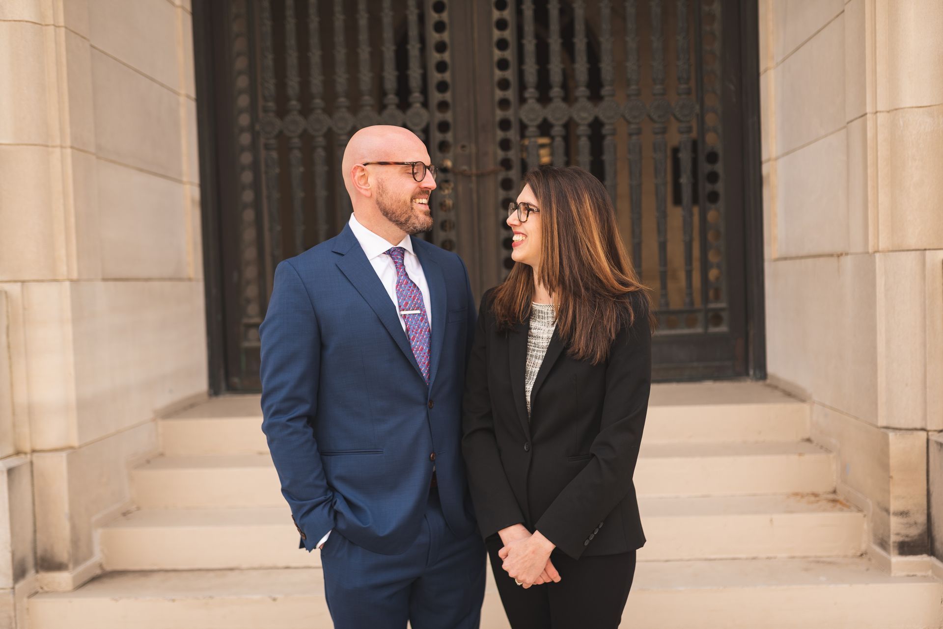 A man and a woman are standing next to each other on the steps of a building.