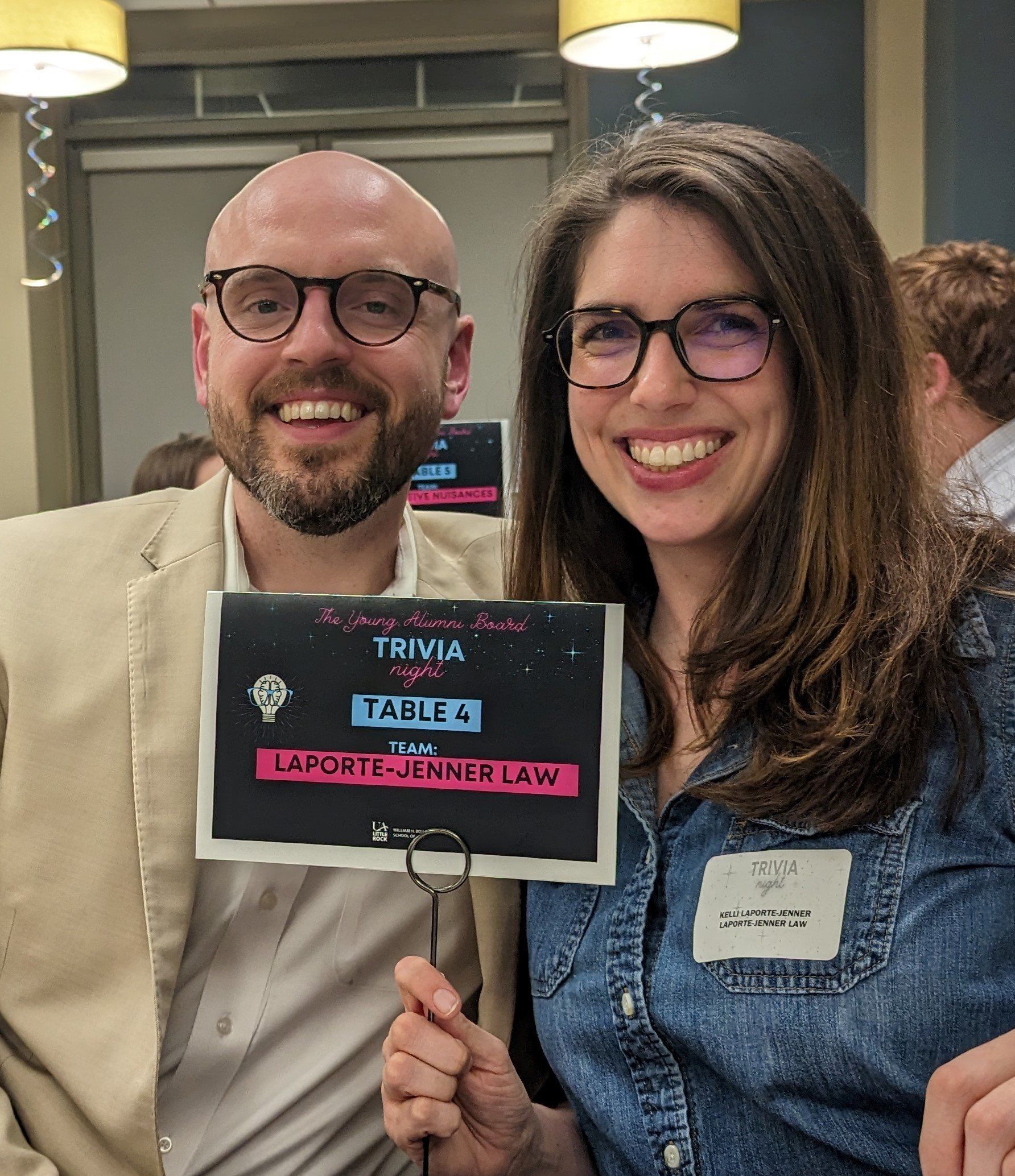 A man and a woman are holding a sign that says trivia tables.