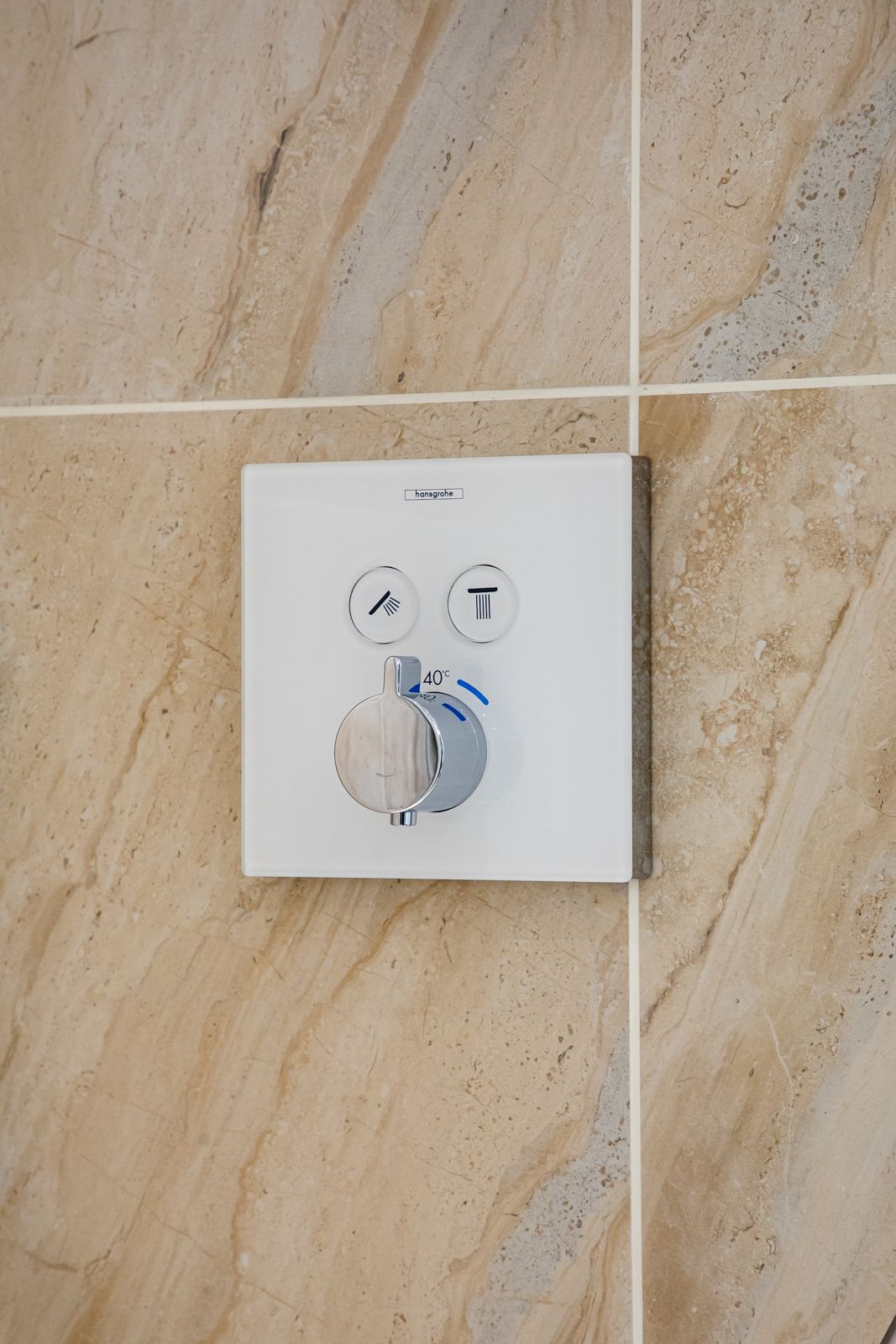 A close up of a shower head on a tiled wall.