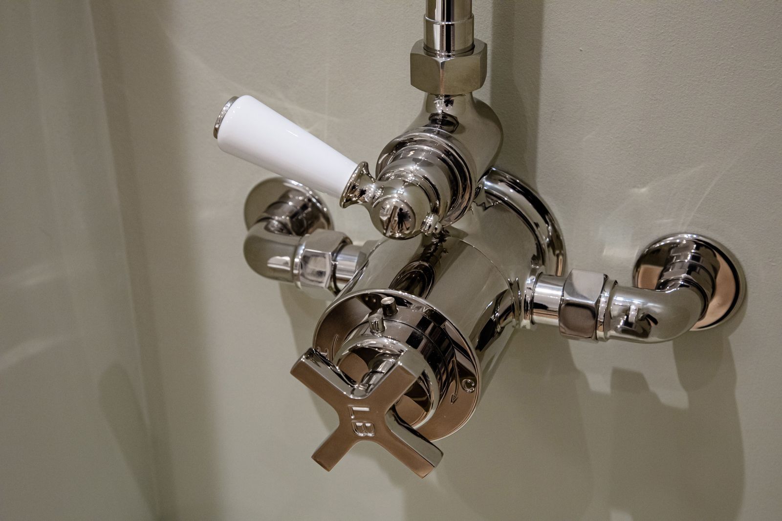 A close up of a shower faucet with a white handle