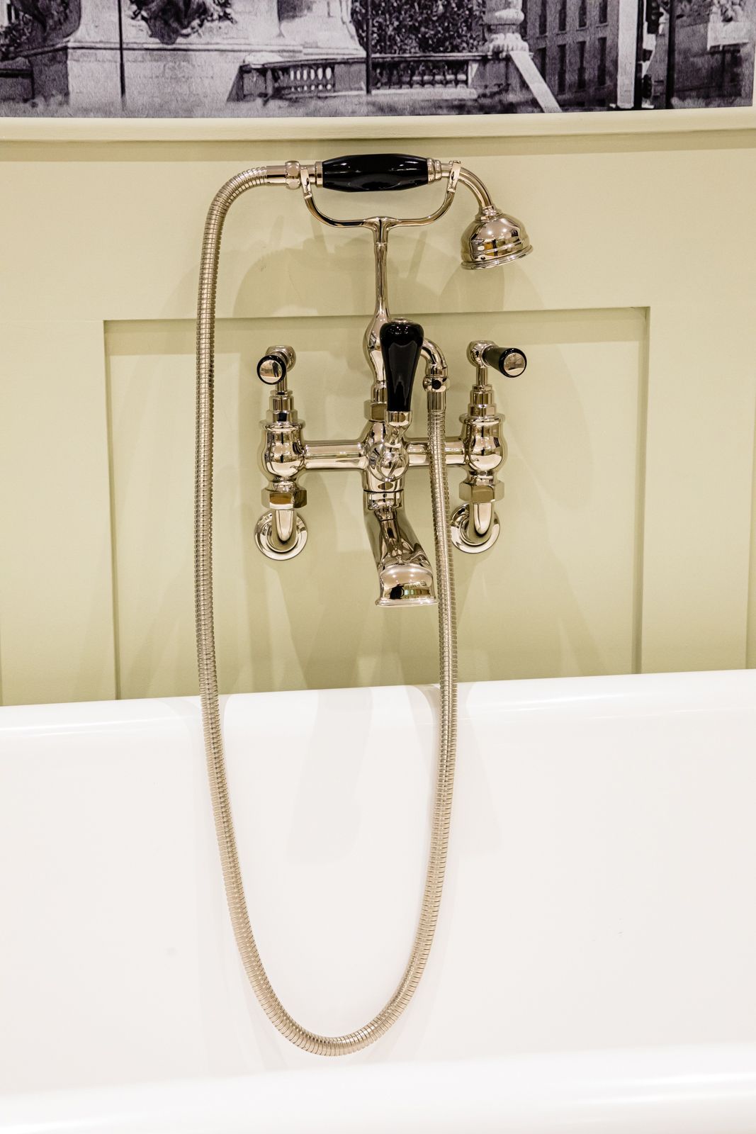 A close up of a bathtub faucet with a hose attached to it.
