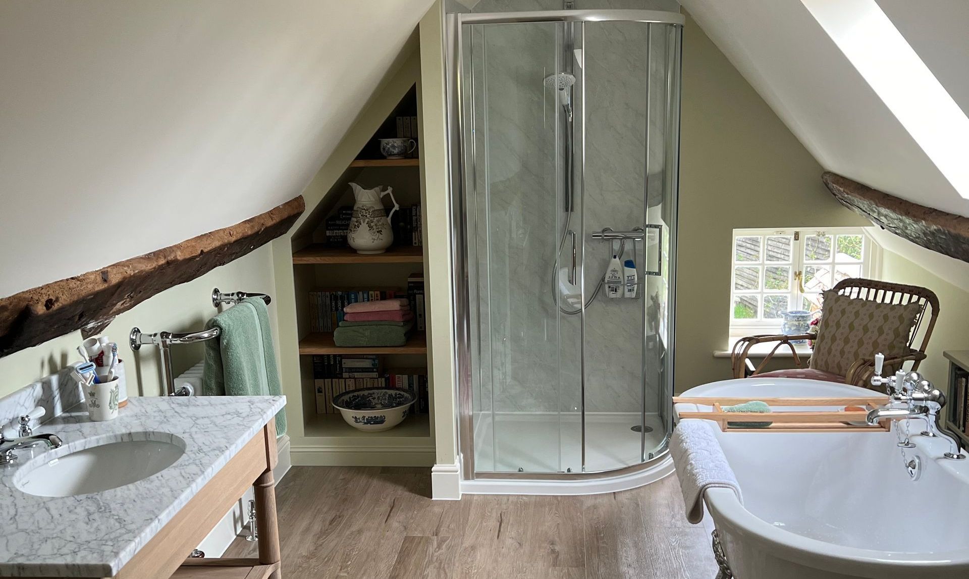 A bathroom with a bathtub , sink , shower and window.