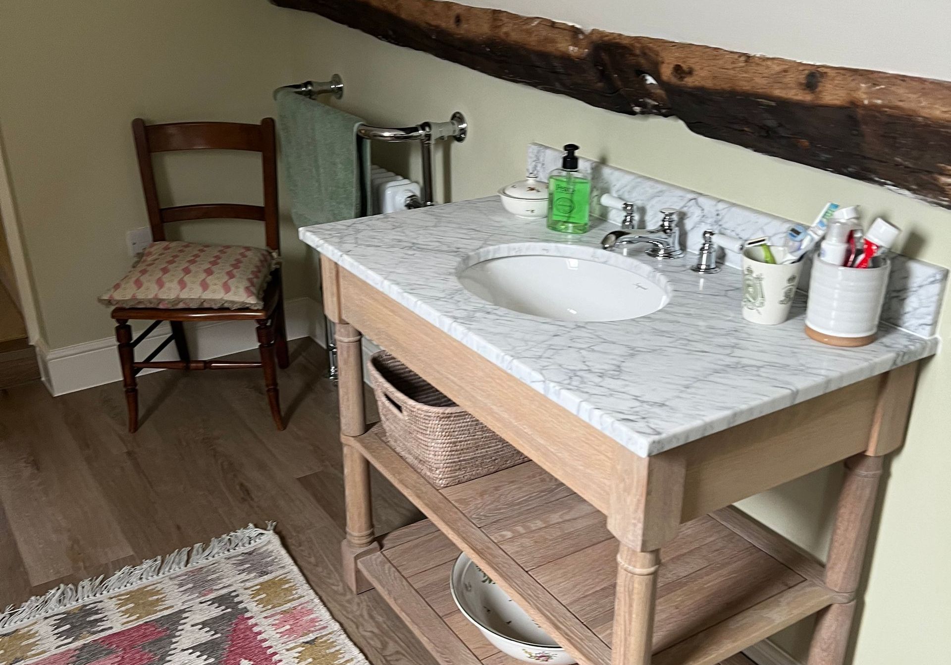 A bathroom with a wooden vanity with a sink and a chair.