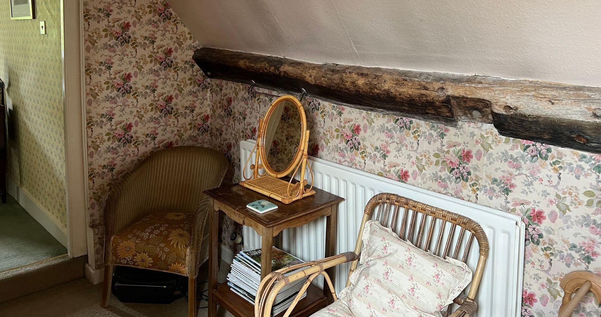 A room with a chair , table , mirror and radiator.