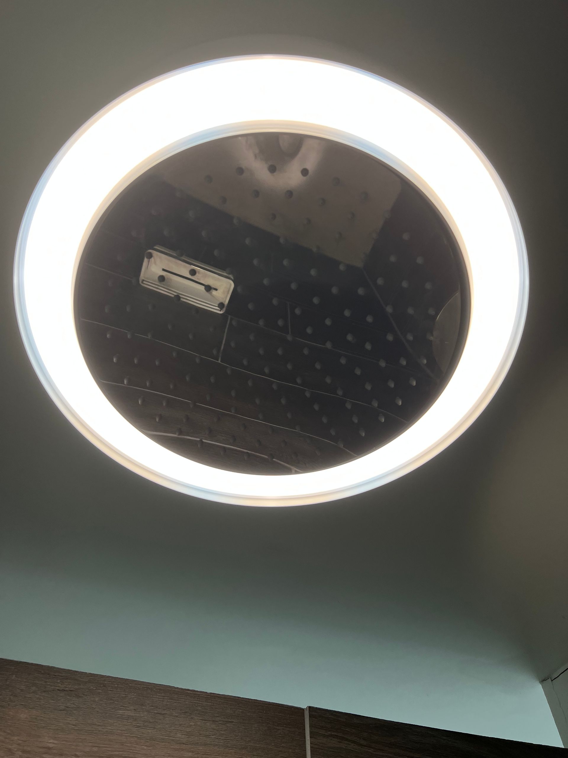 A round light is hanging from the ceiling above a mirror