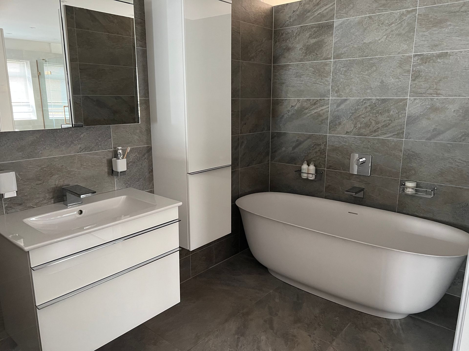 A bathroom with a bathtub , sink and mirror.