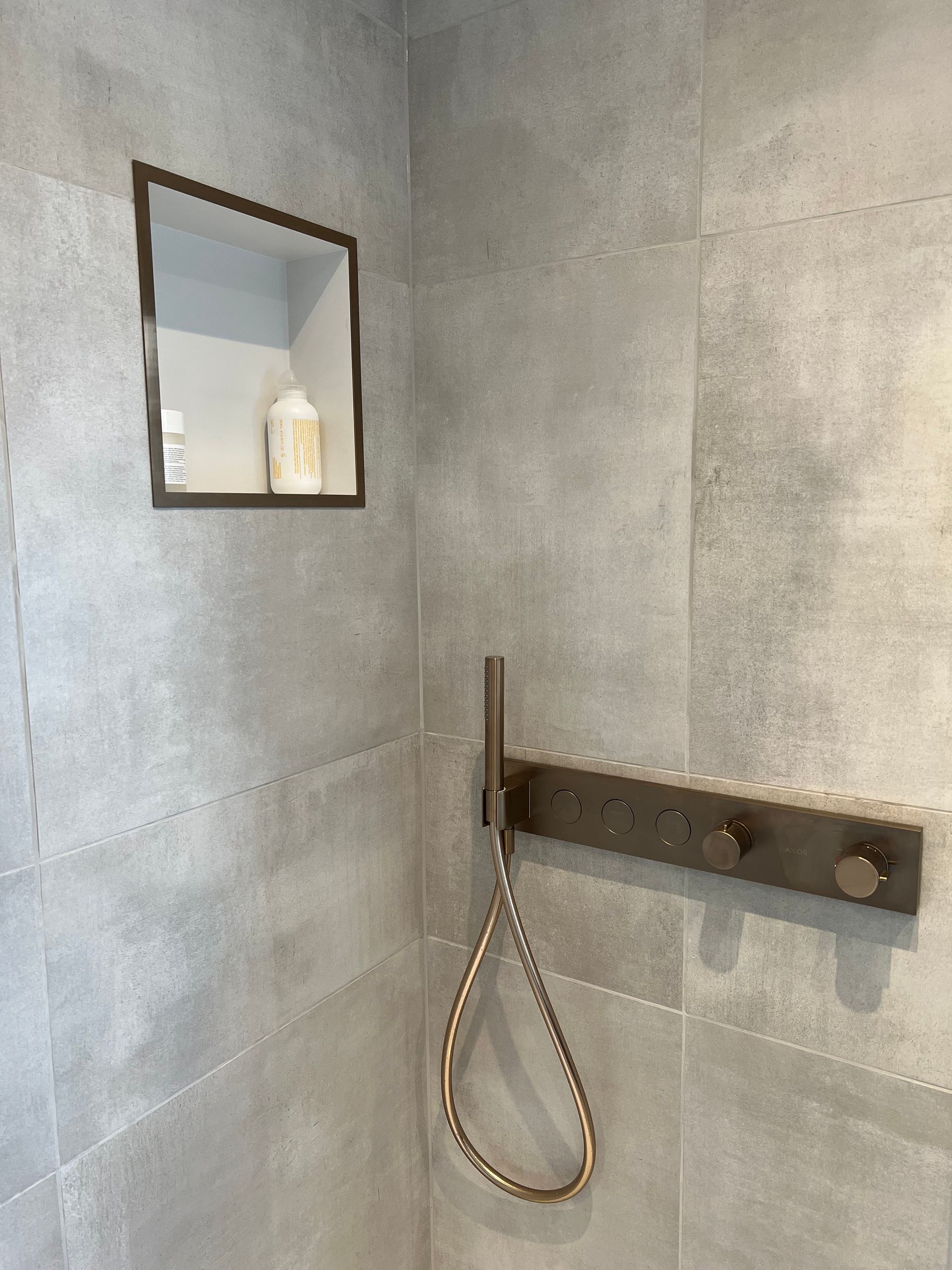 A bathroom with a shower head and a mirror on the wall.