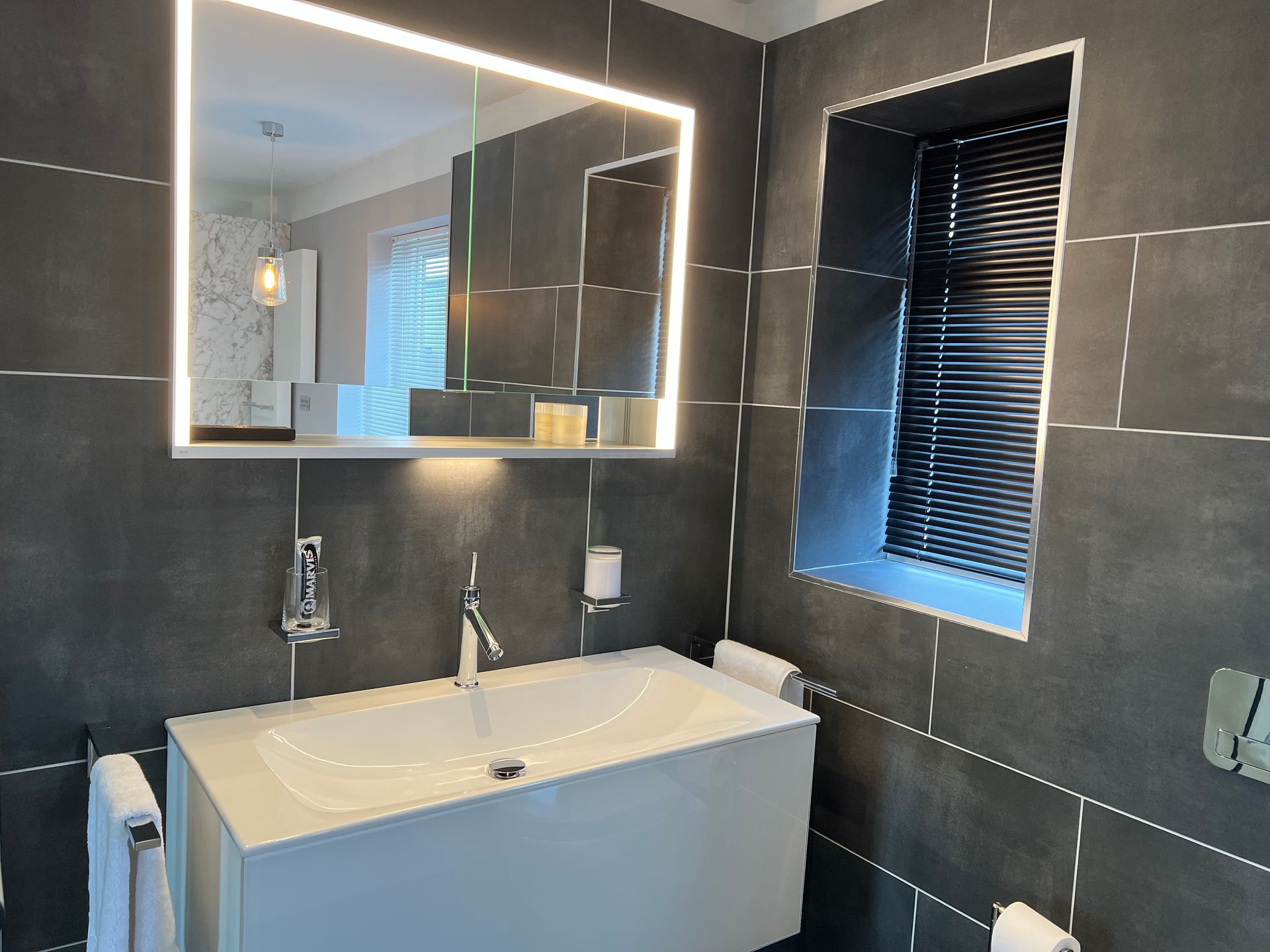 A bathroom with a sink , mirror and window