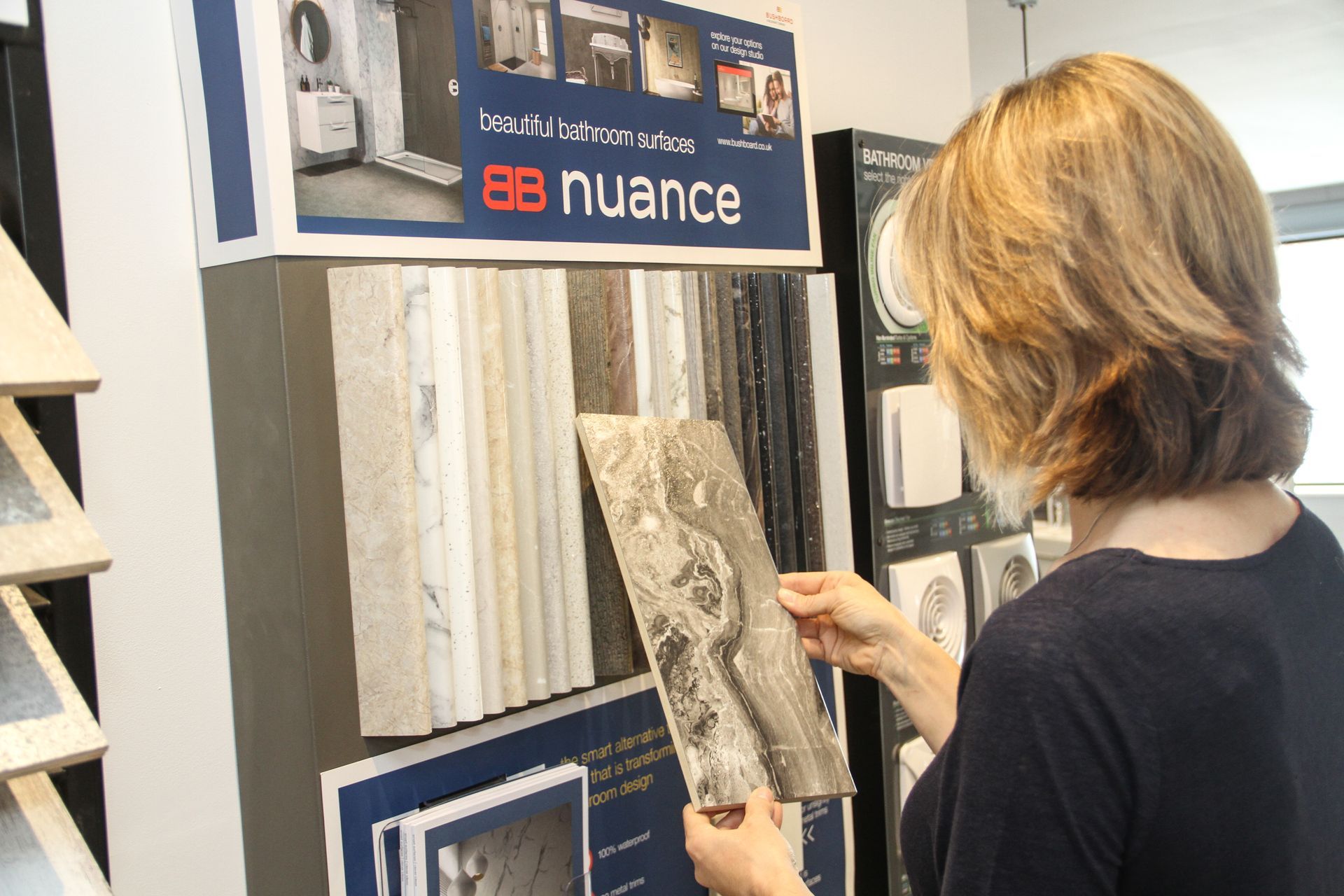 A woman is looking at a tile display in a store.