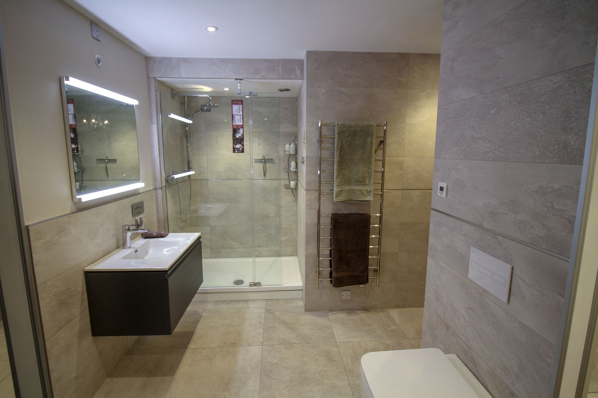 A bathroom with a walk in shower , sink , toilet and mirror.
