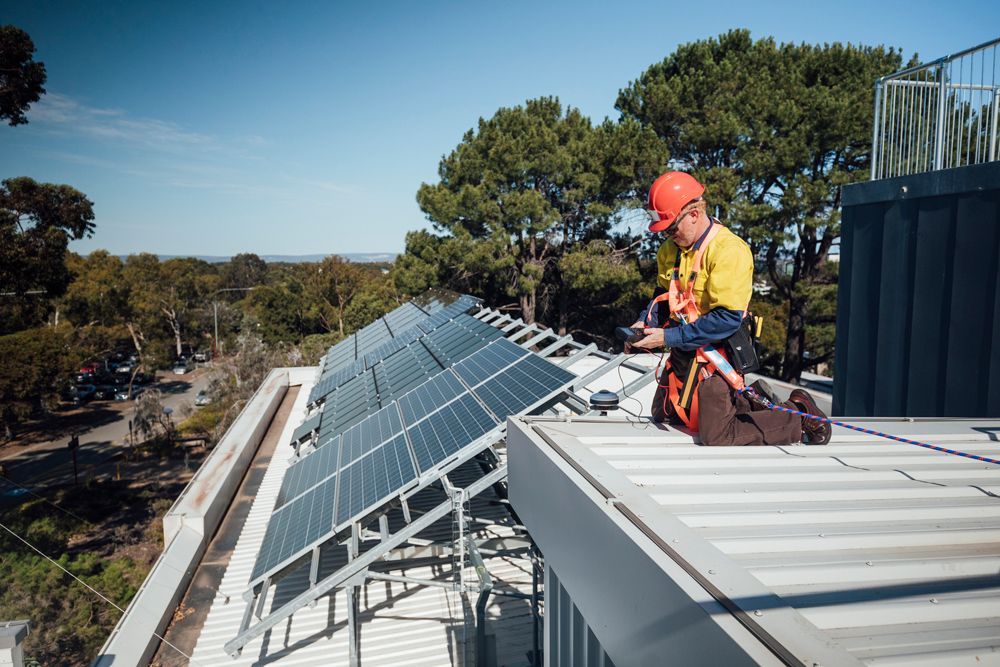 A man is installing solar panels on the roof of a building