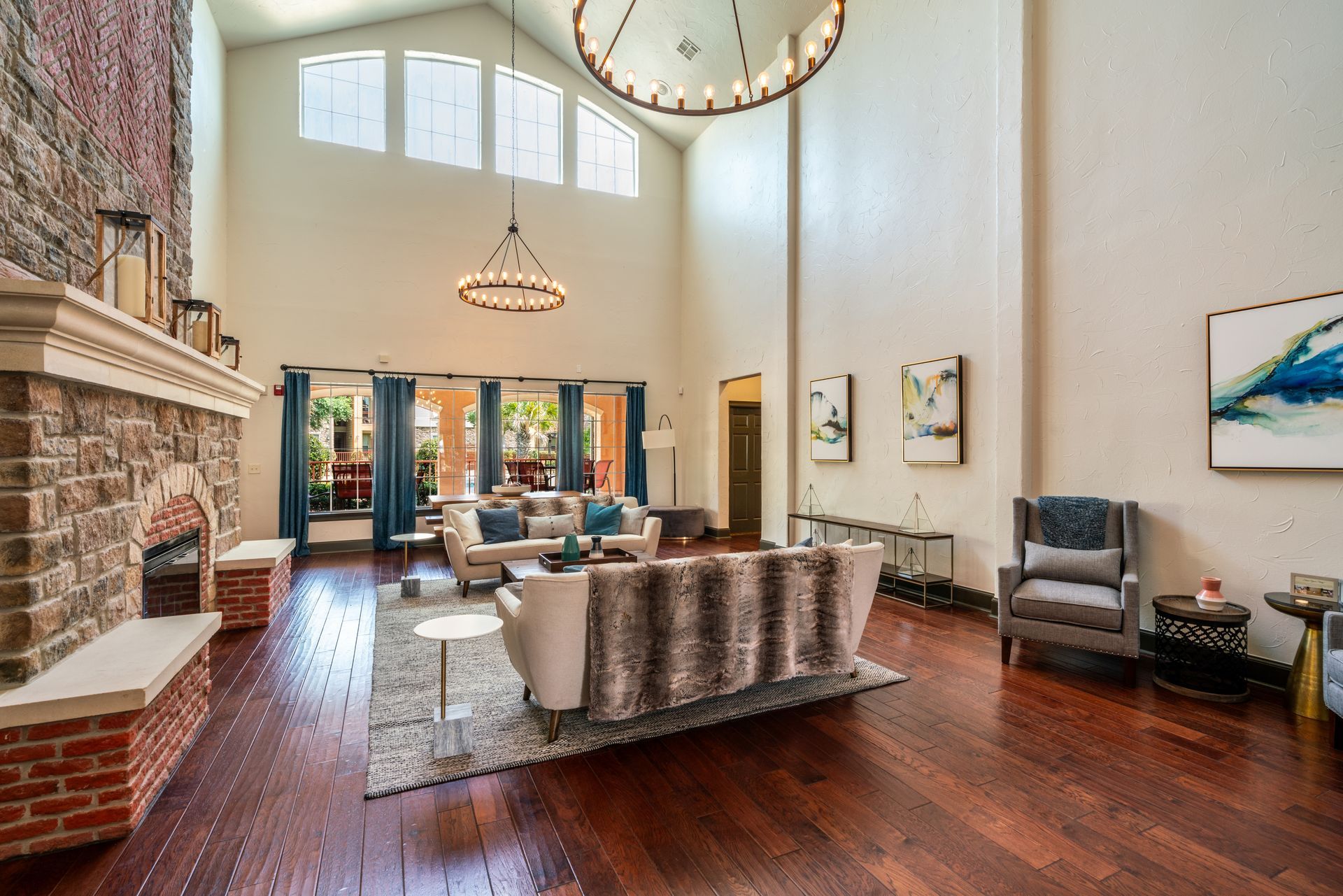 Spacious living room with a fireplace, light walls, and large windows overlooking a patio.