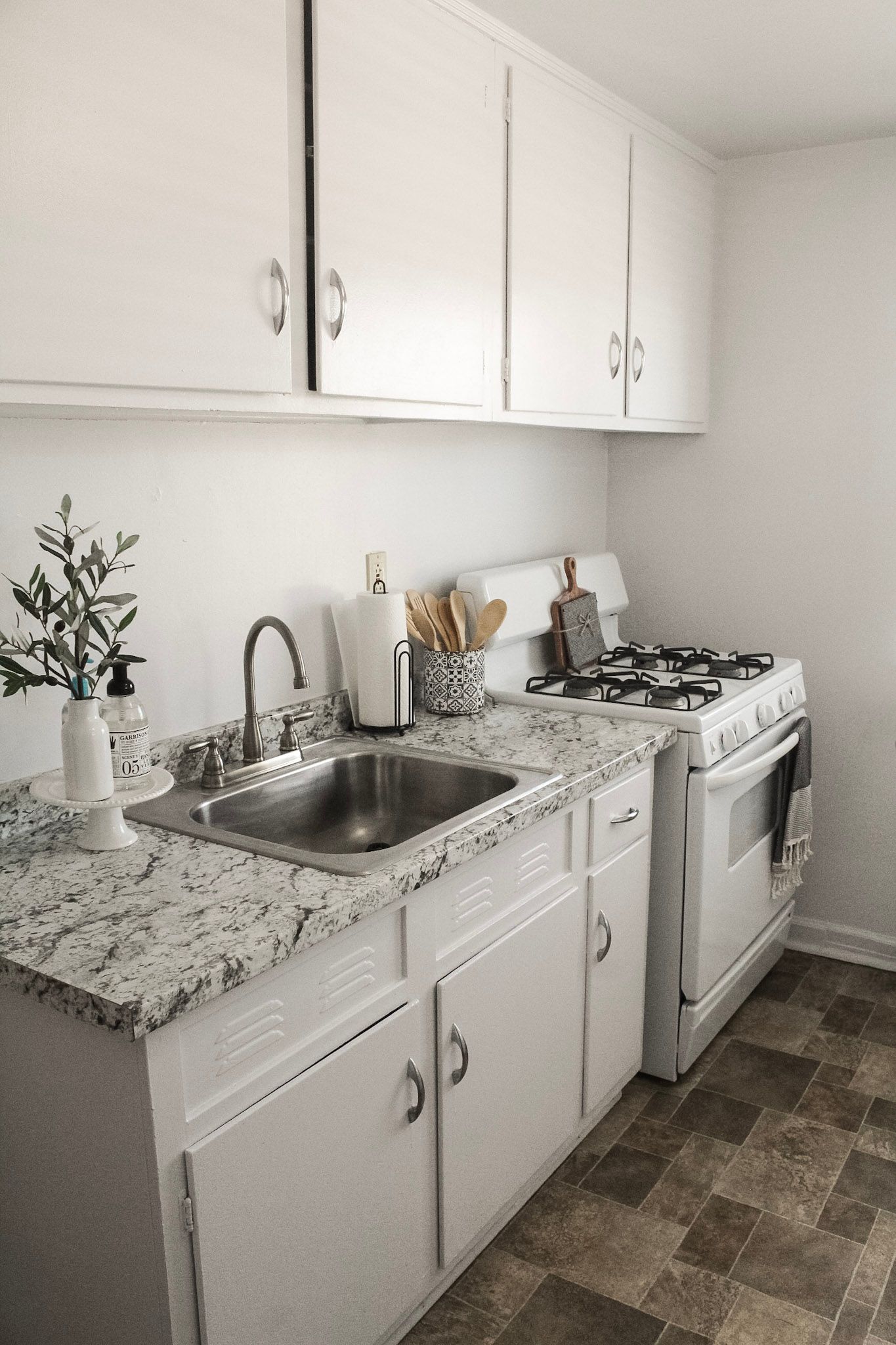 A kitchen with white cabinets , granite counter tops , a sink , stove and oven.