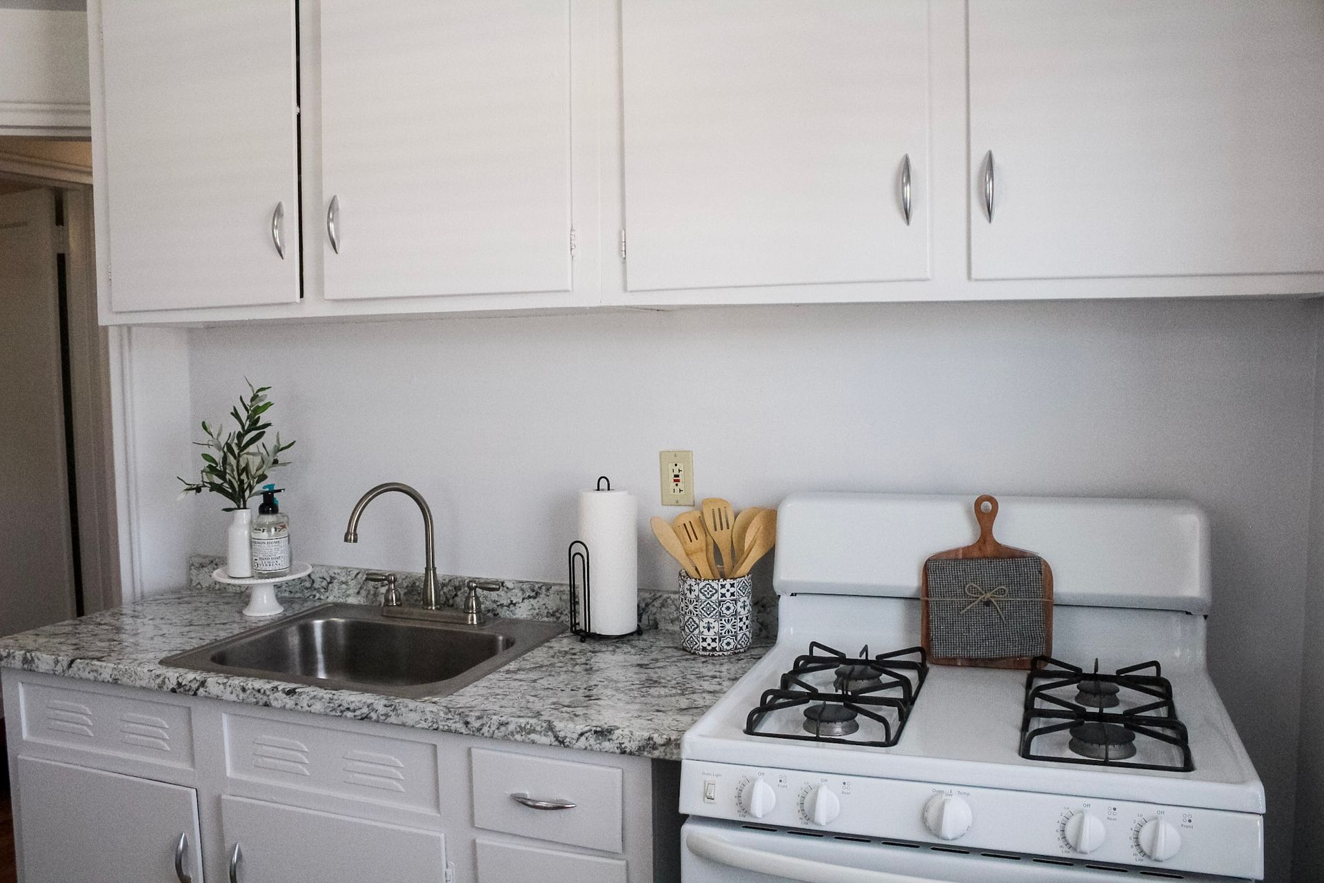 A kitchen with white cabinets and a stove and sink