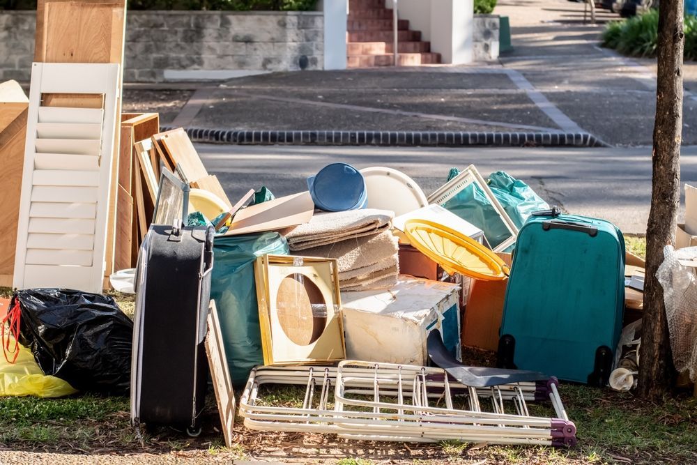 Pile of discarded furniture and household items stacked by a curb outdoors