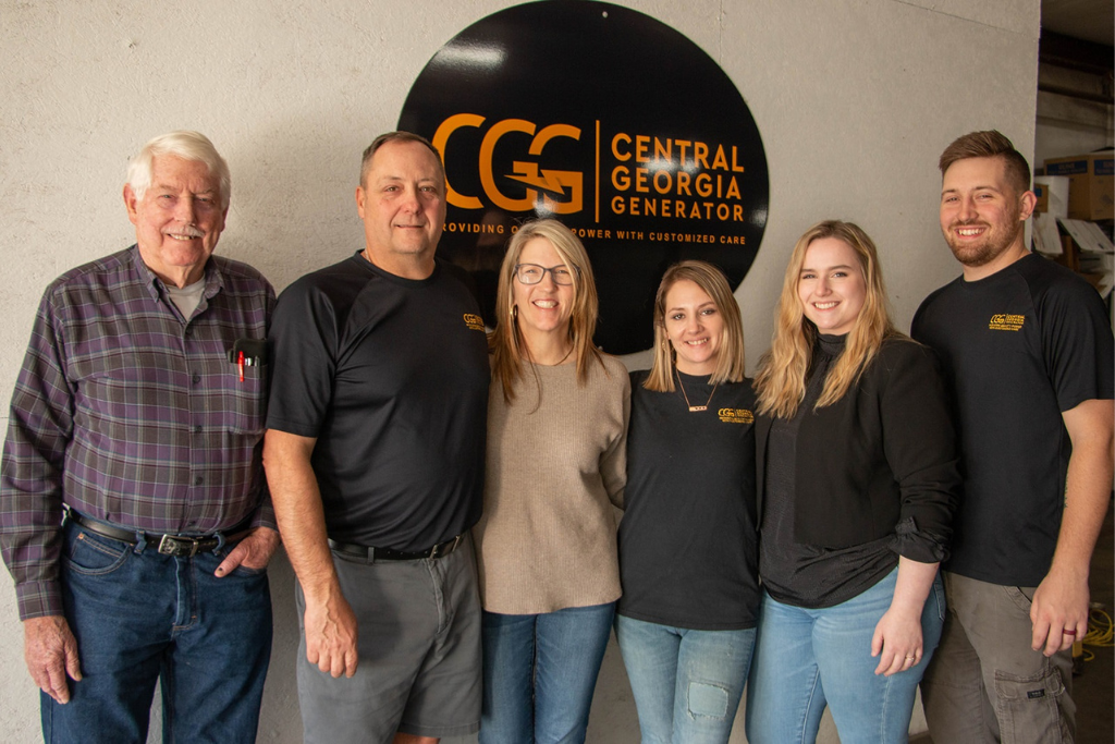 Staff of CGG standing together in front of the CGG sign