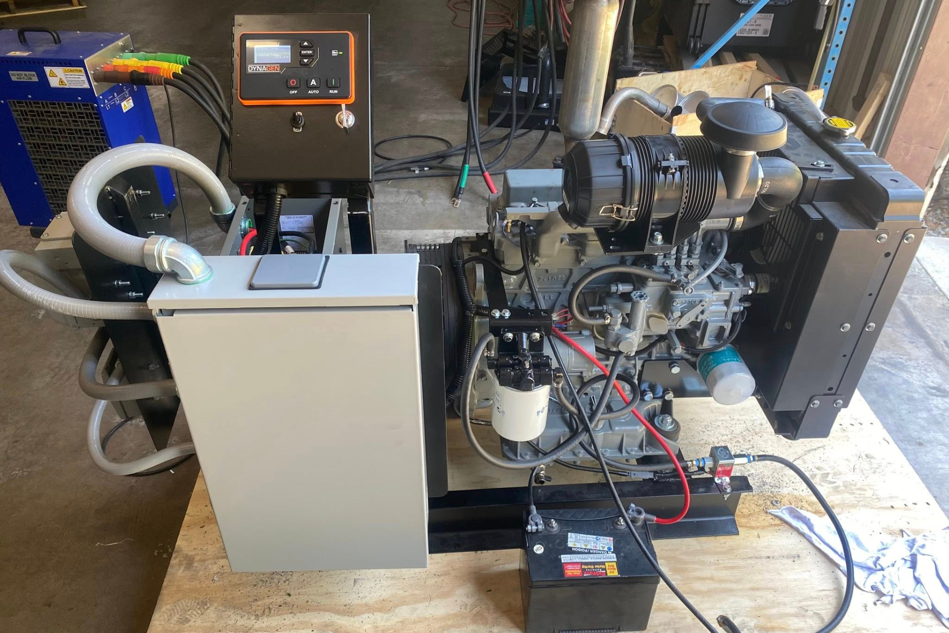 Diesel engine generator with control panel, battery, and exhaust system on a wooden pallet.