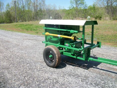 A green trailer is parked on the side of a gravel road