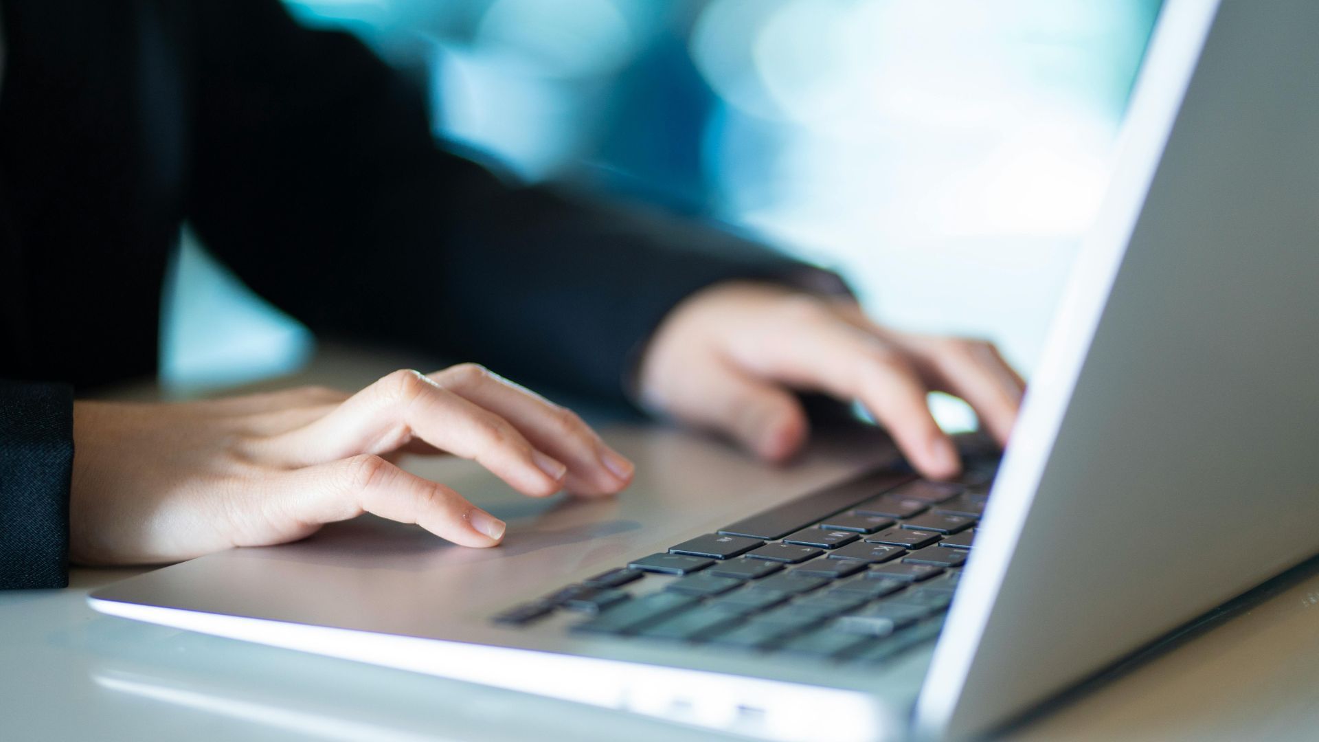 A hand holds a yellow paper umbrella over a miniature house, a car, and a family of three against a green background.