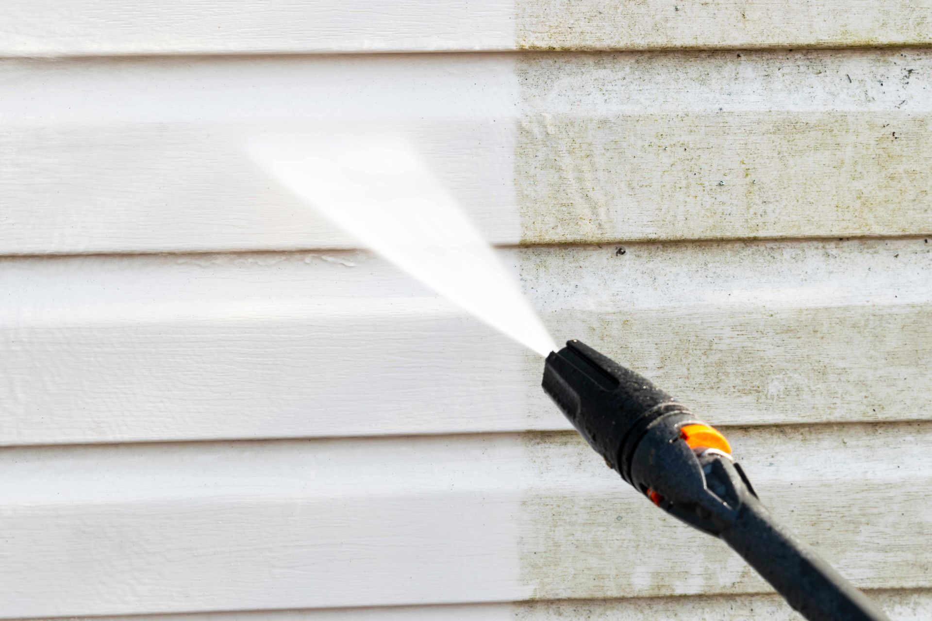 Exterior pressure washing on vinyl siding showing removal of dirt mold and grime with strong power.