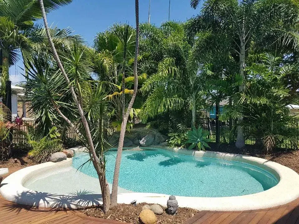 A Large Swimming Pool Surrounded By Palm Trees And Rocks — Tropical North Swimming Pools 'n' Spas In Currajong, QLD