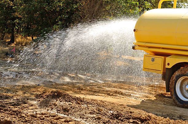 Worker using a hydroseed hose to spray mulch on a hillside.