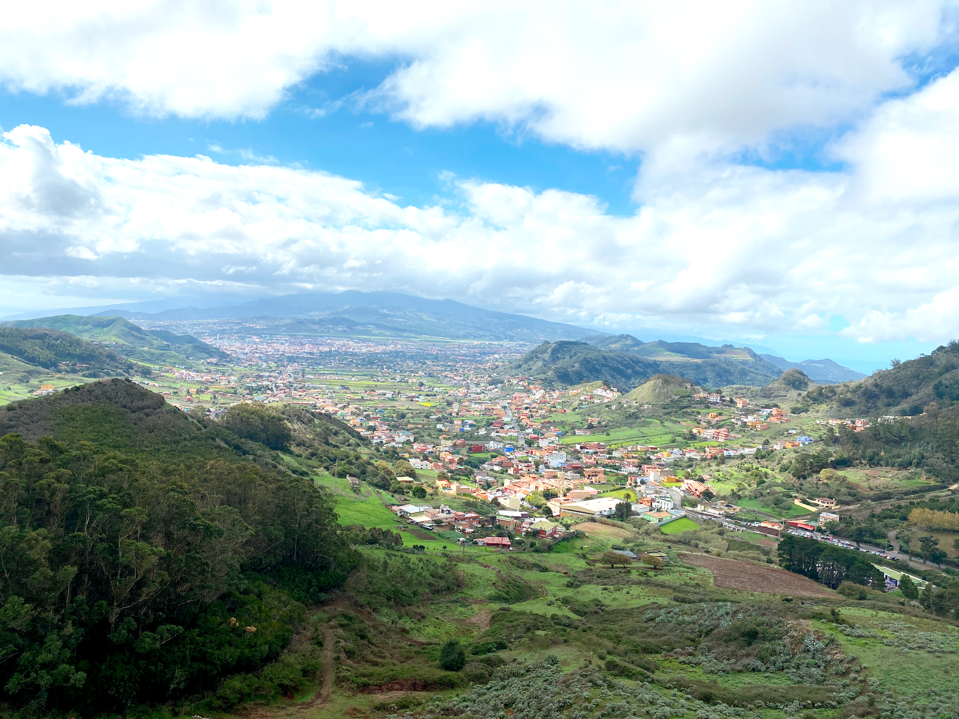 A view of a small town in the middle of a valley with mountains in the background.