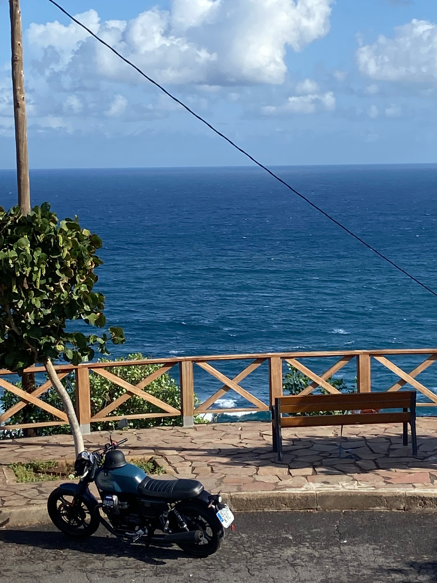 A motorcycle is parked on the side of the road near the ocean