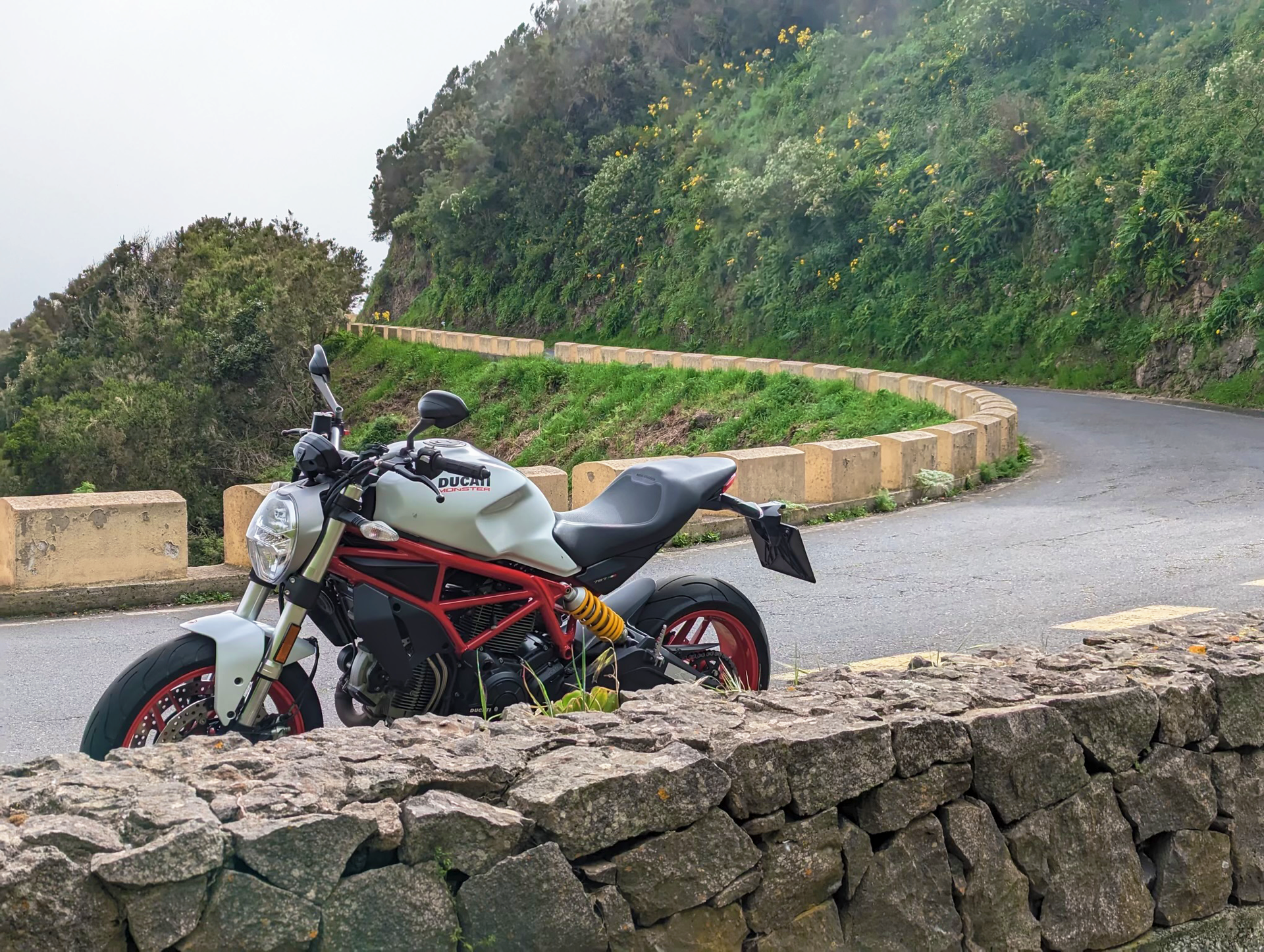 A motorcycle is parked on the side of a curvy road.
