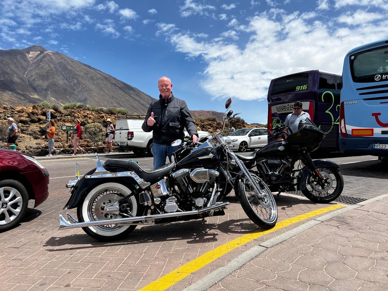A man is standing next to a motorcycle in a parking lot.