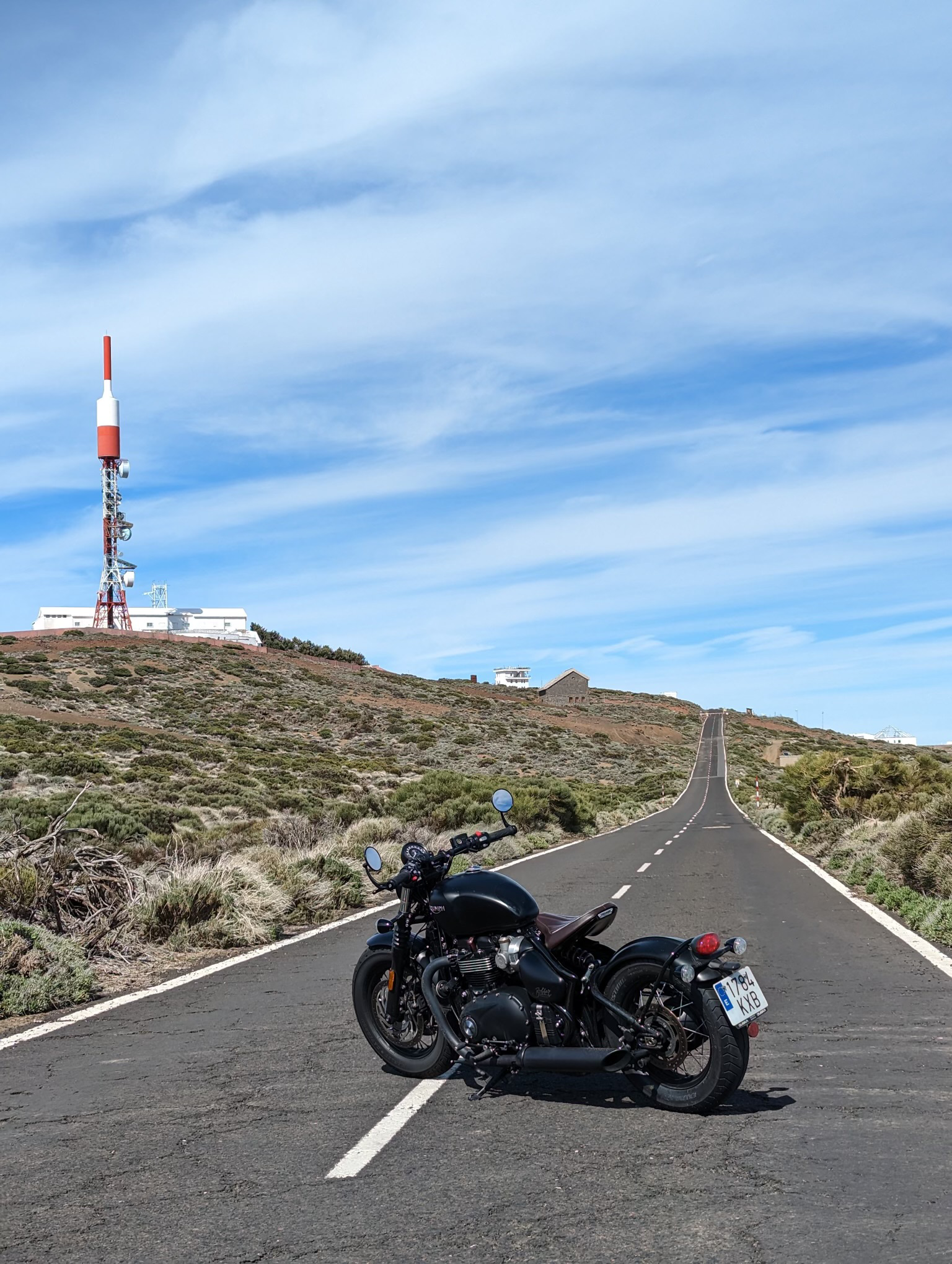 A black motorcycle is parked on the side of a road.