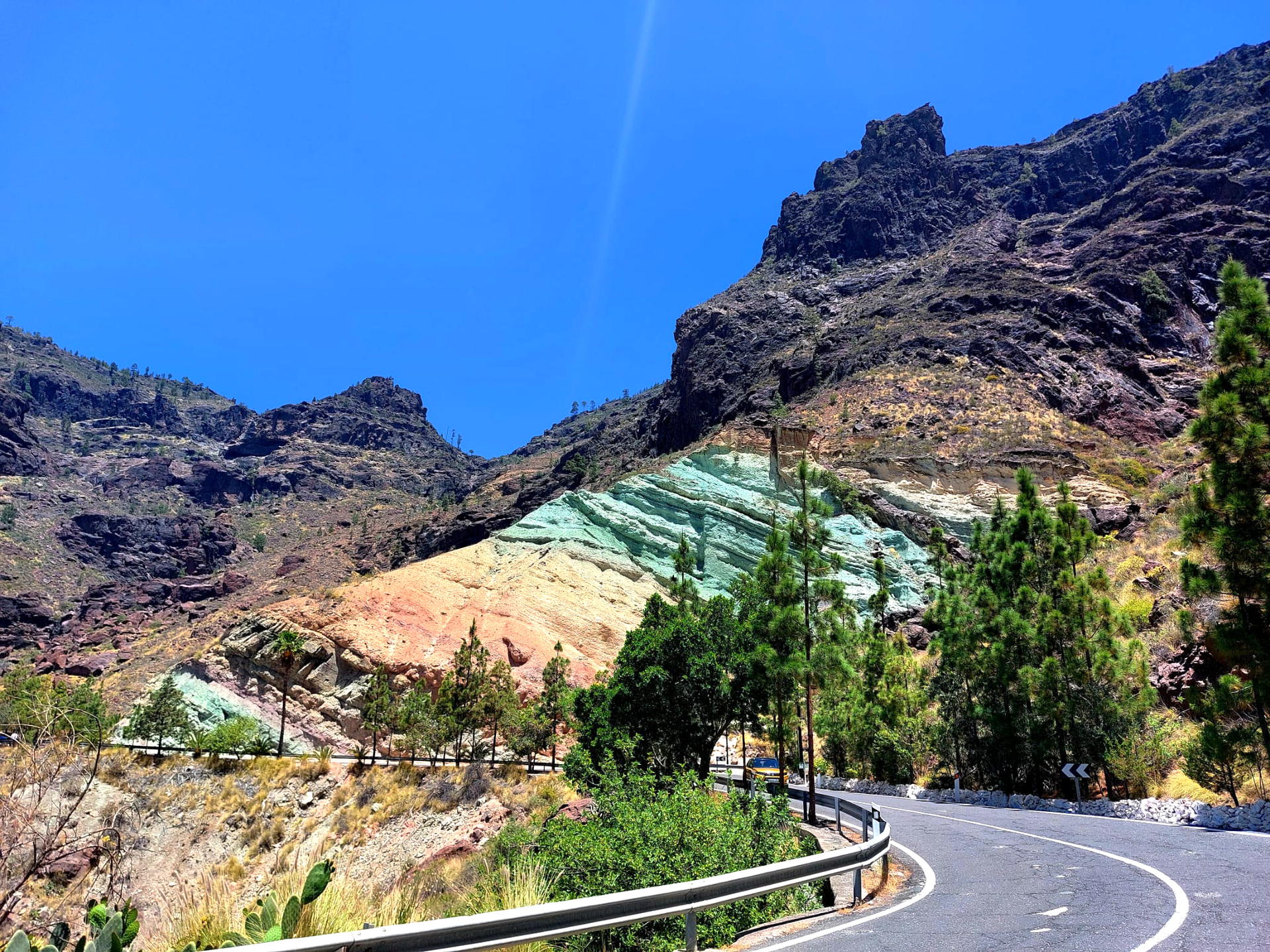 A road going through a mountainous area with trees and mountains in the background.