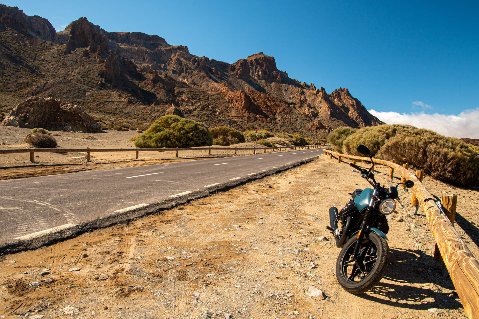 A motorcycle is parked on the side of the road in the desert.