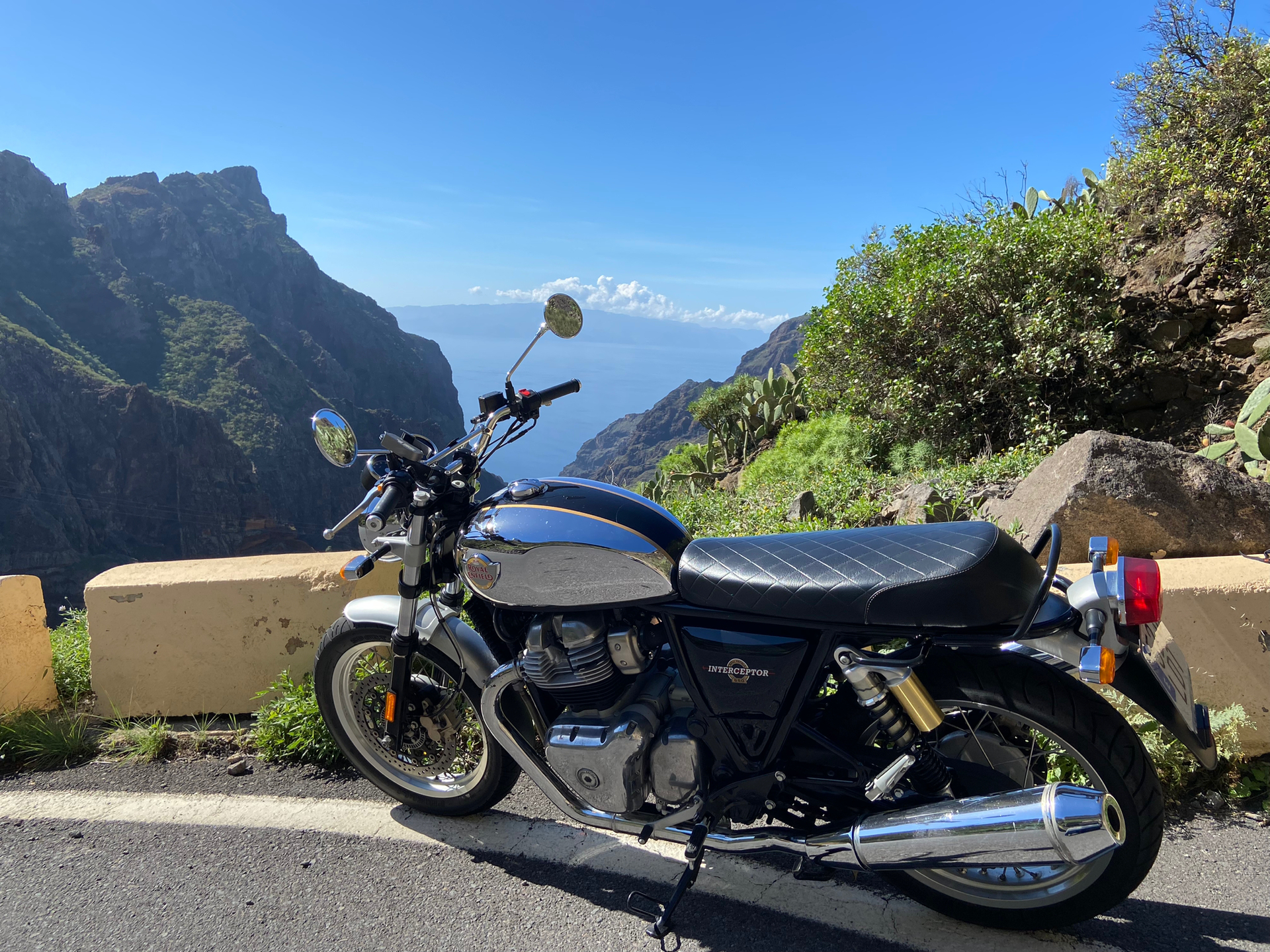 A motorcycle is parked on the side of a road next to a mountain.