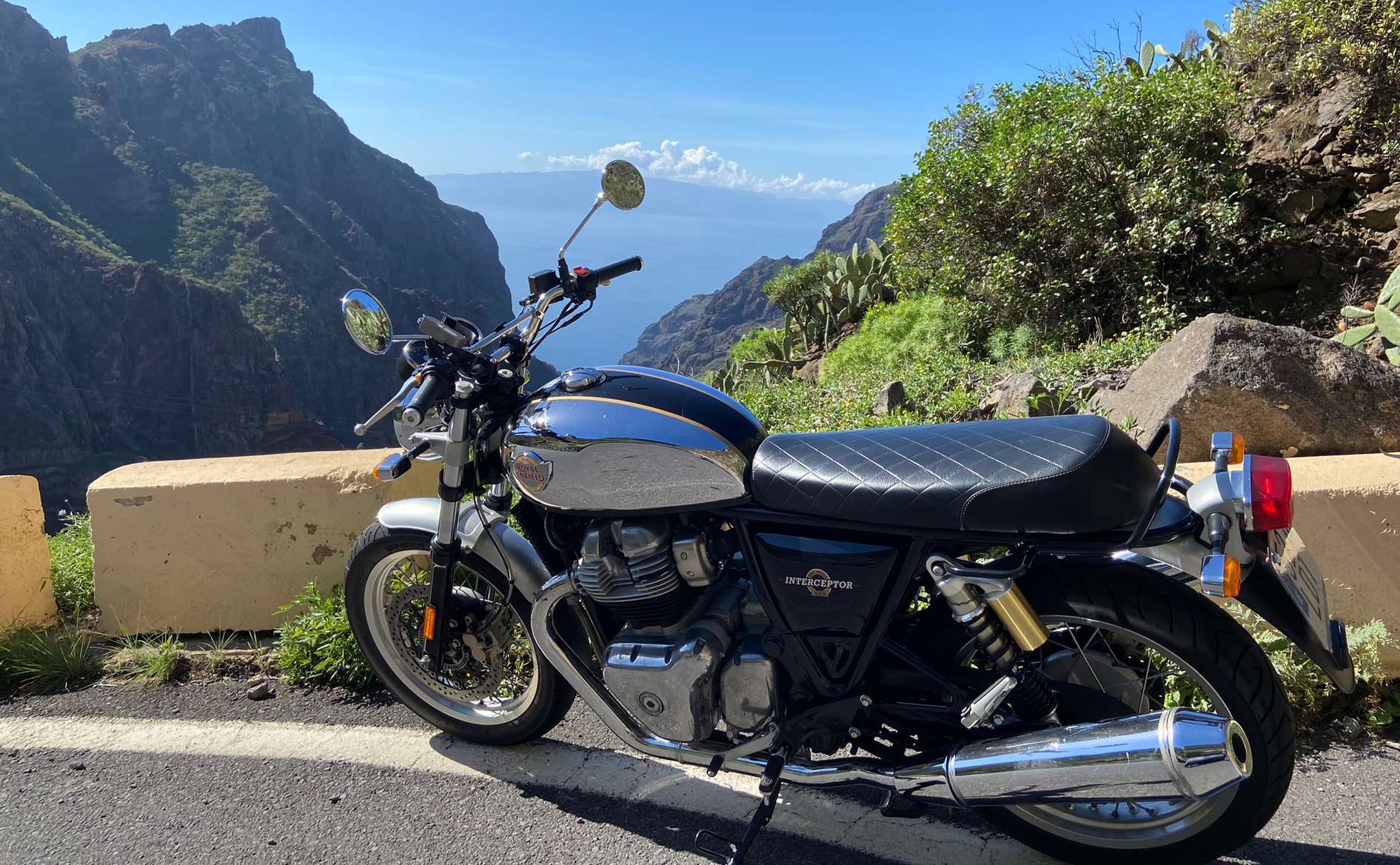 A motorcycle is parked on the side of a road next to a mountain.