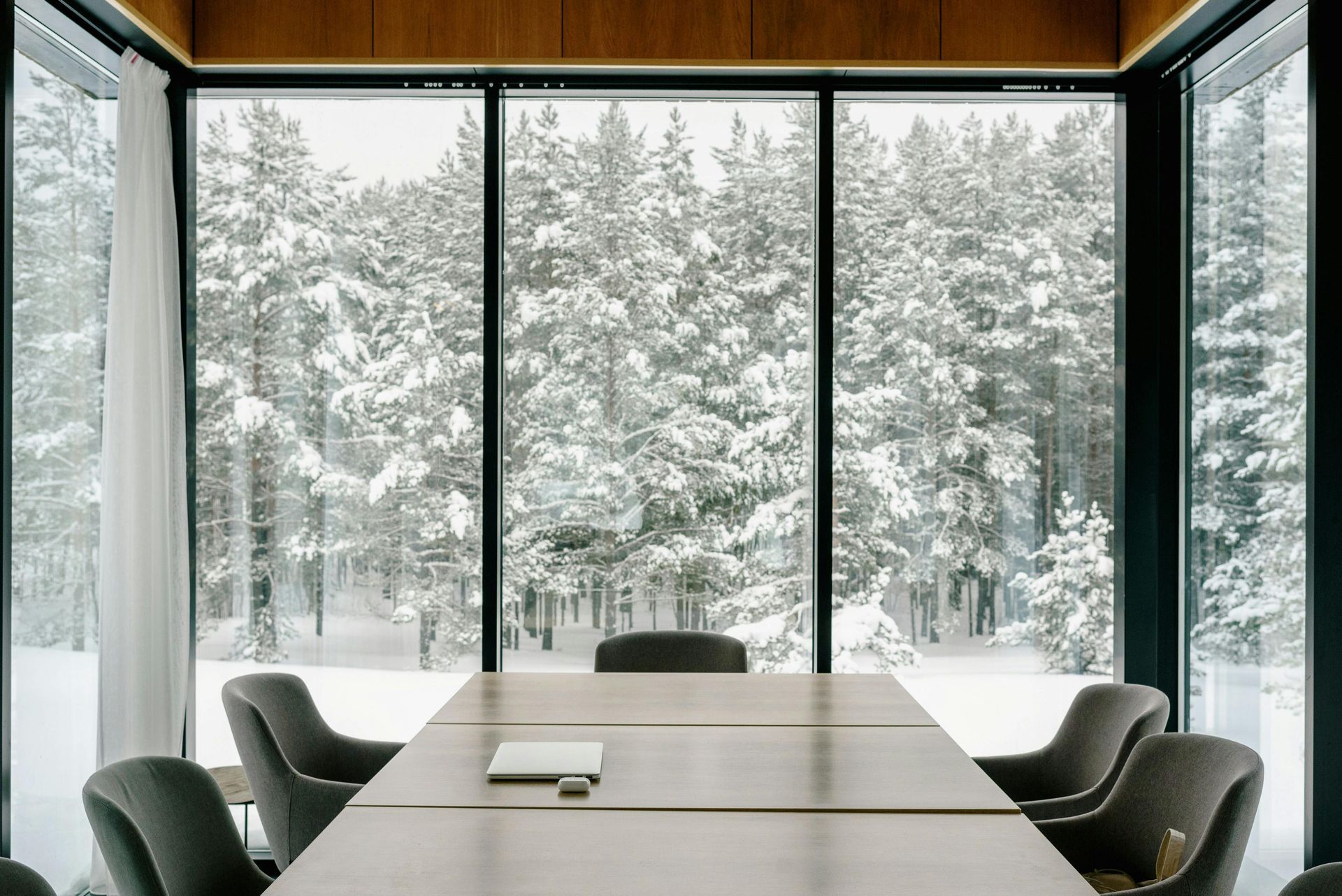 A conference room with a table and chairs and a view of a snowy forest.