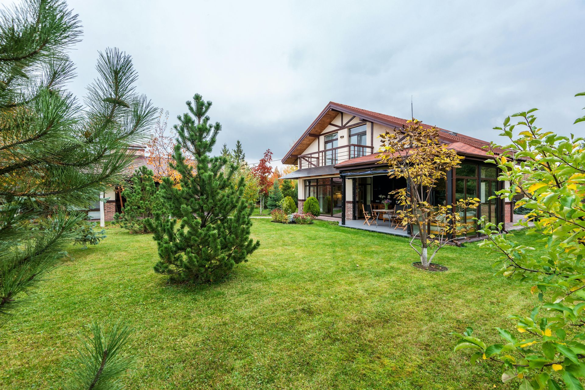 A house with a large lawn and trees in front of it.
