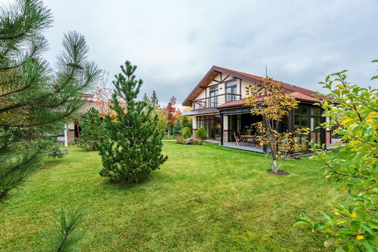 A house with a large lawn and trees in front of it.