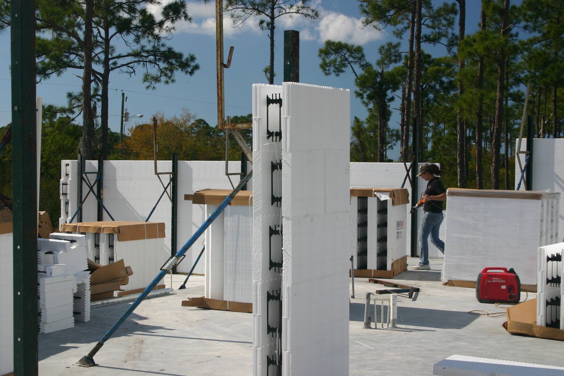 Construction site with insulated concrete form walls, a person walking, and equipment.