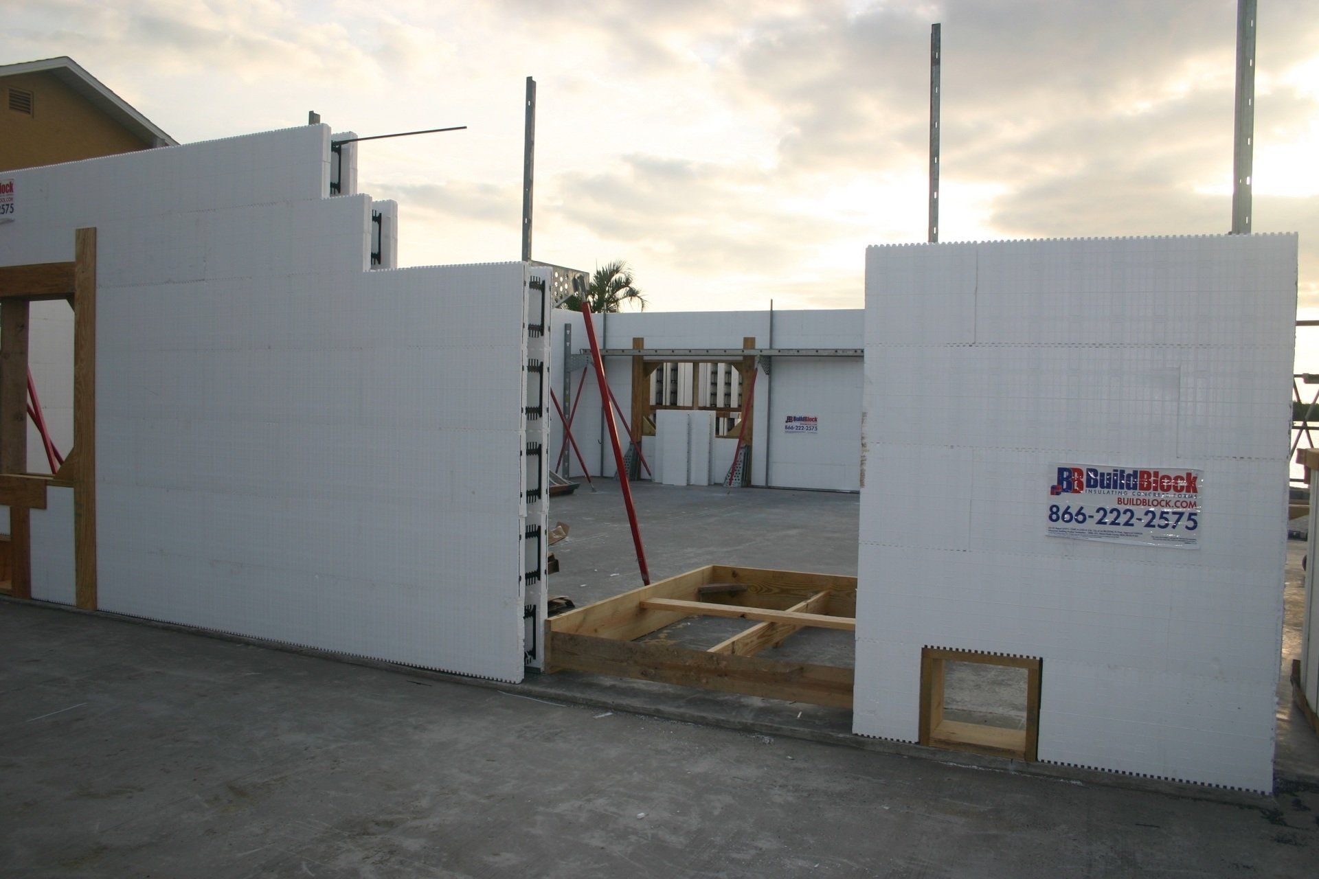 ICF wall construction; white foam blocks forming house exterior; wooden supports; overcast sky.