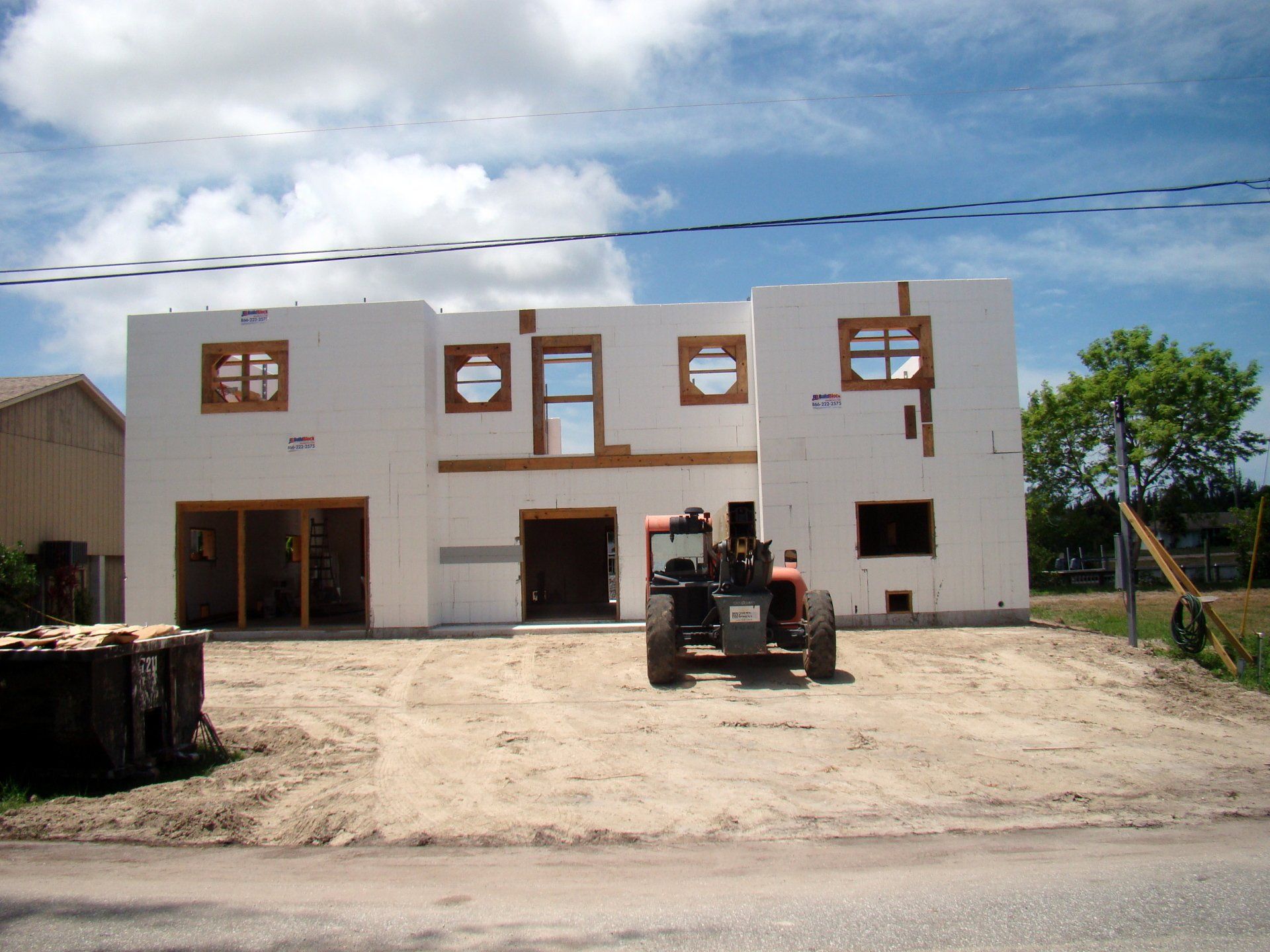 Construction site with a two-story white building with circular and rectangular window frames.
