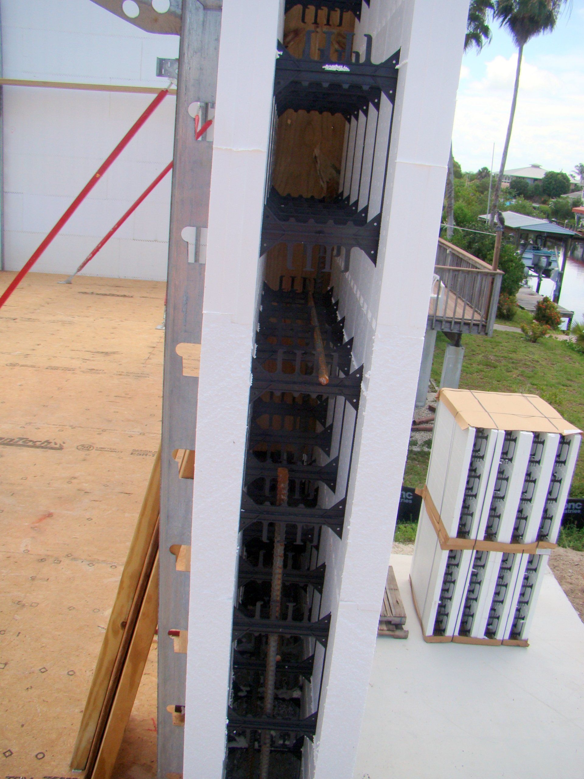 Construction site with stacked white wall panels, black supports, and wood framing.