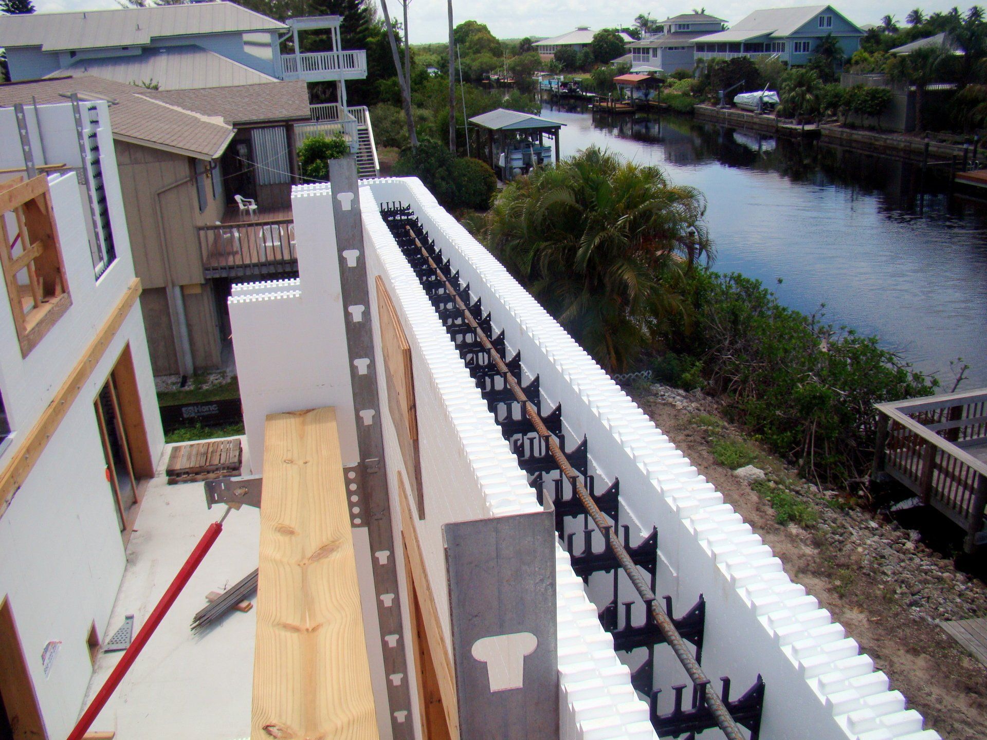 Construction site with white insulated concrete forms along a canal.