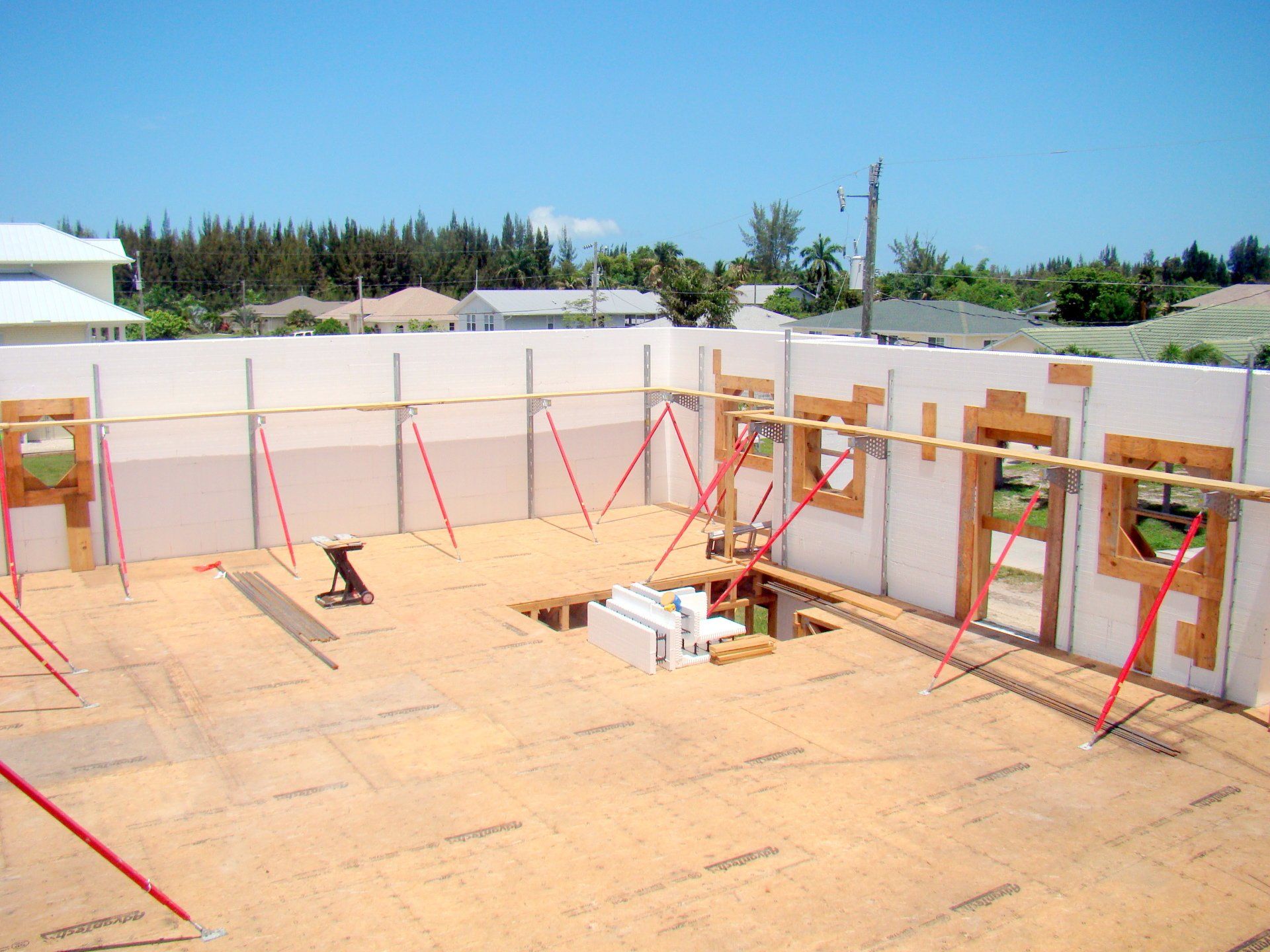 Construction site with insulated concrete form (ICF) walls. Wooden floor and support beams. Blue sky background.