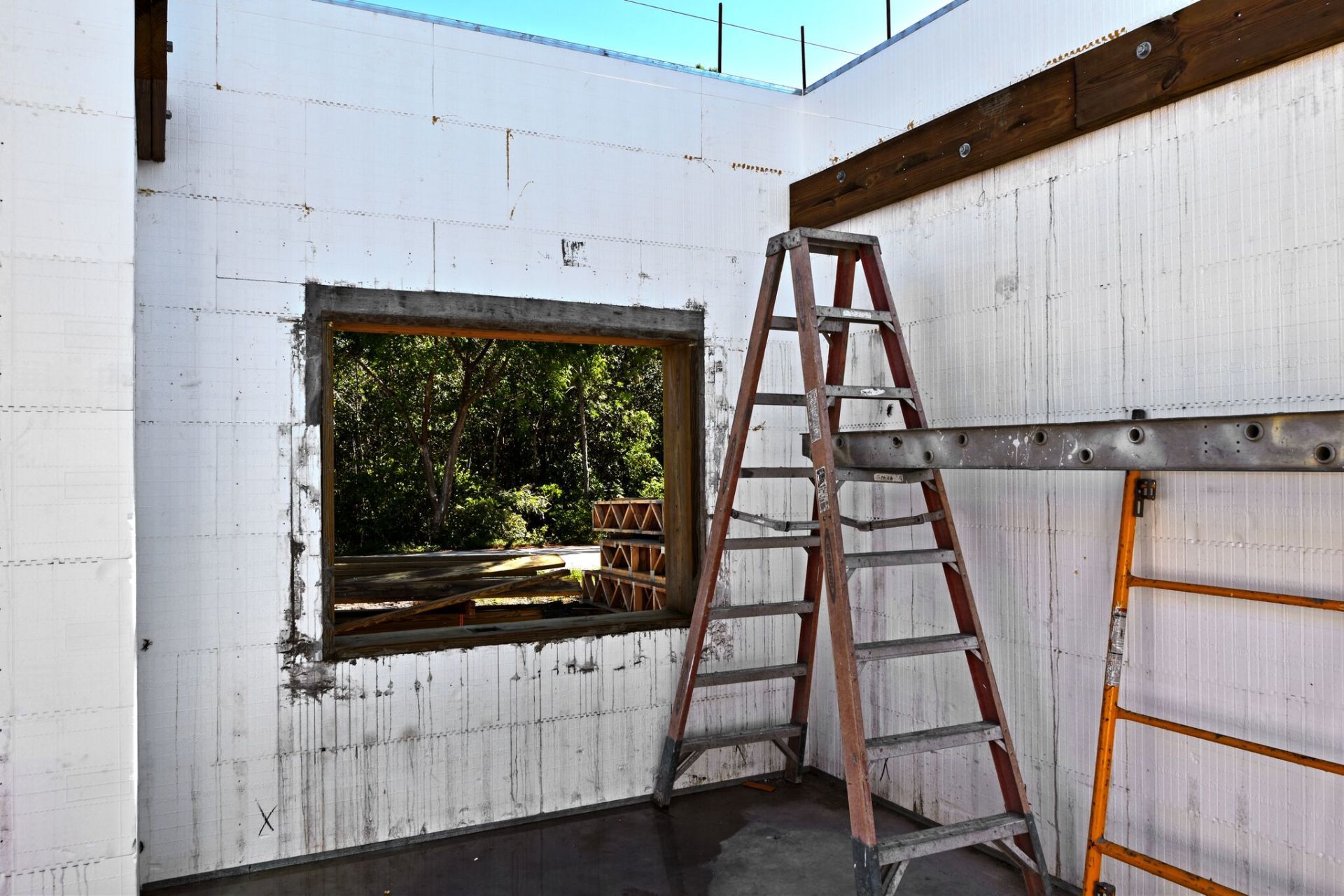 Interior construction site with ladder, window, and block walls.