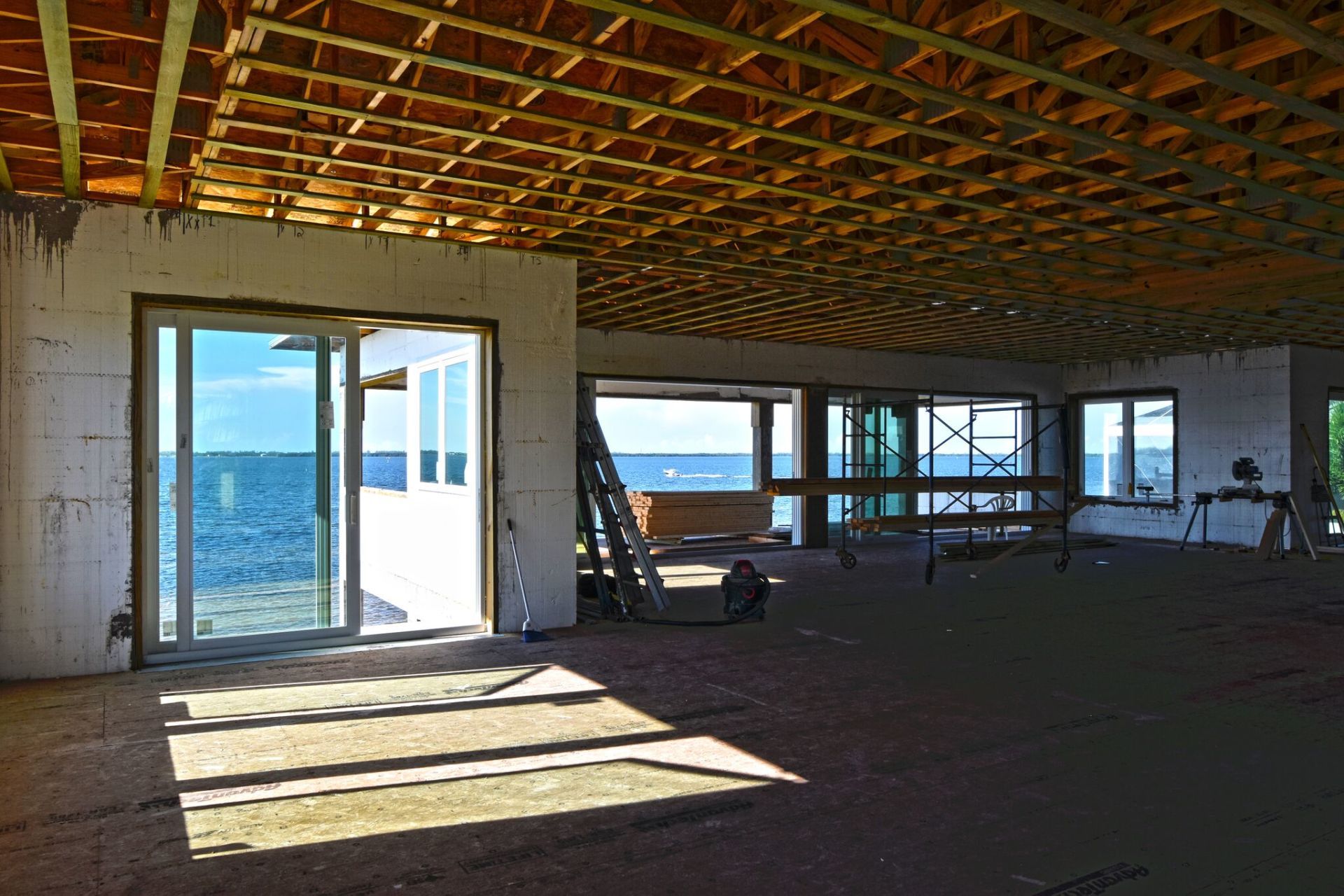 Interior under construction with ocean view through windows and sliding door.
