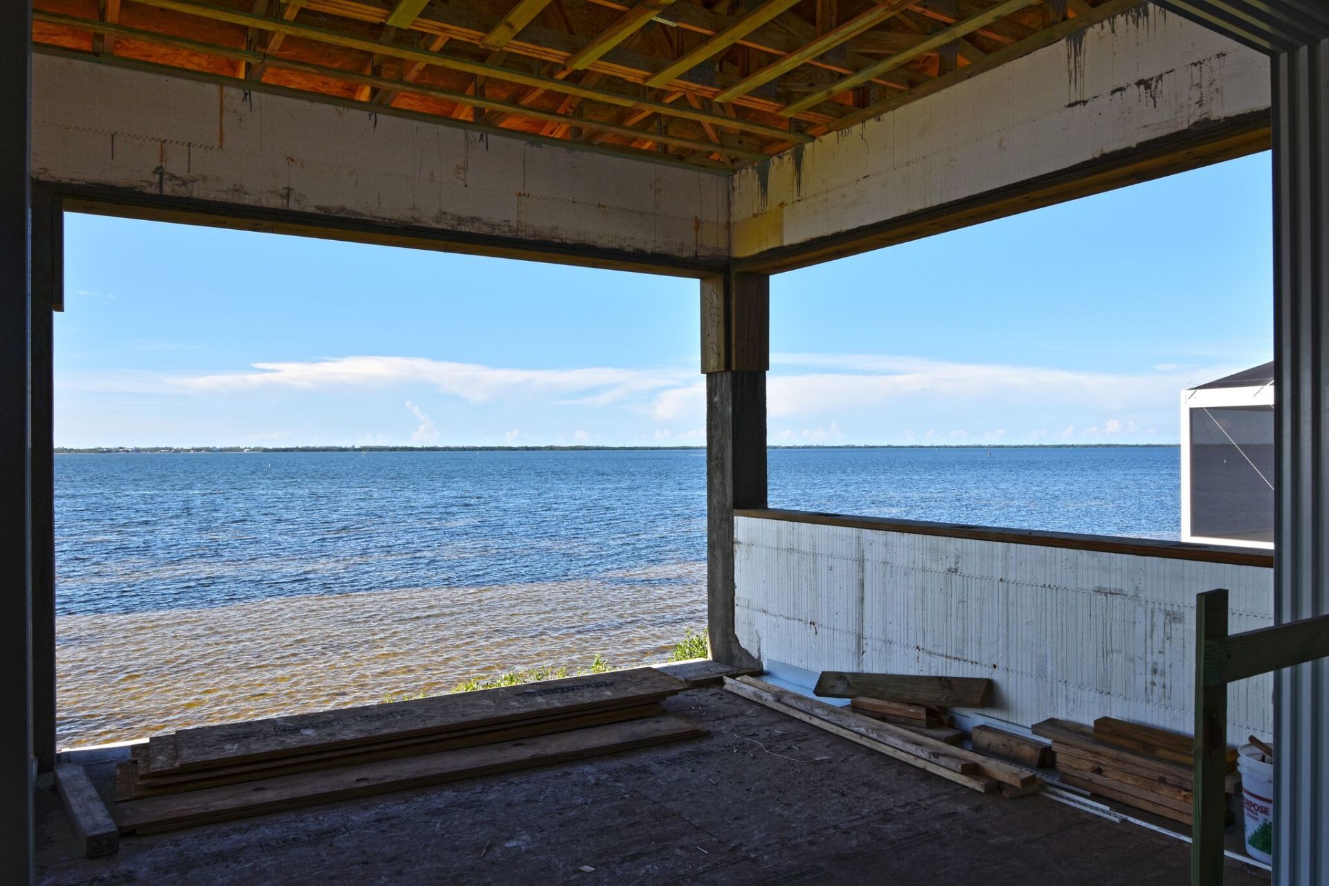 Construction framing a wide ocean view with a blue sky. Interior view of a building under construction.