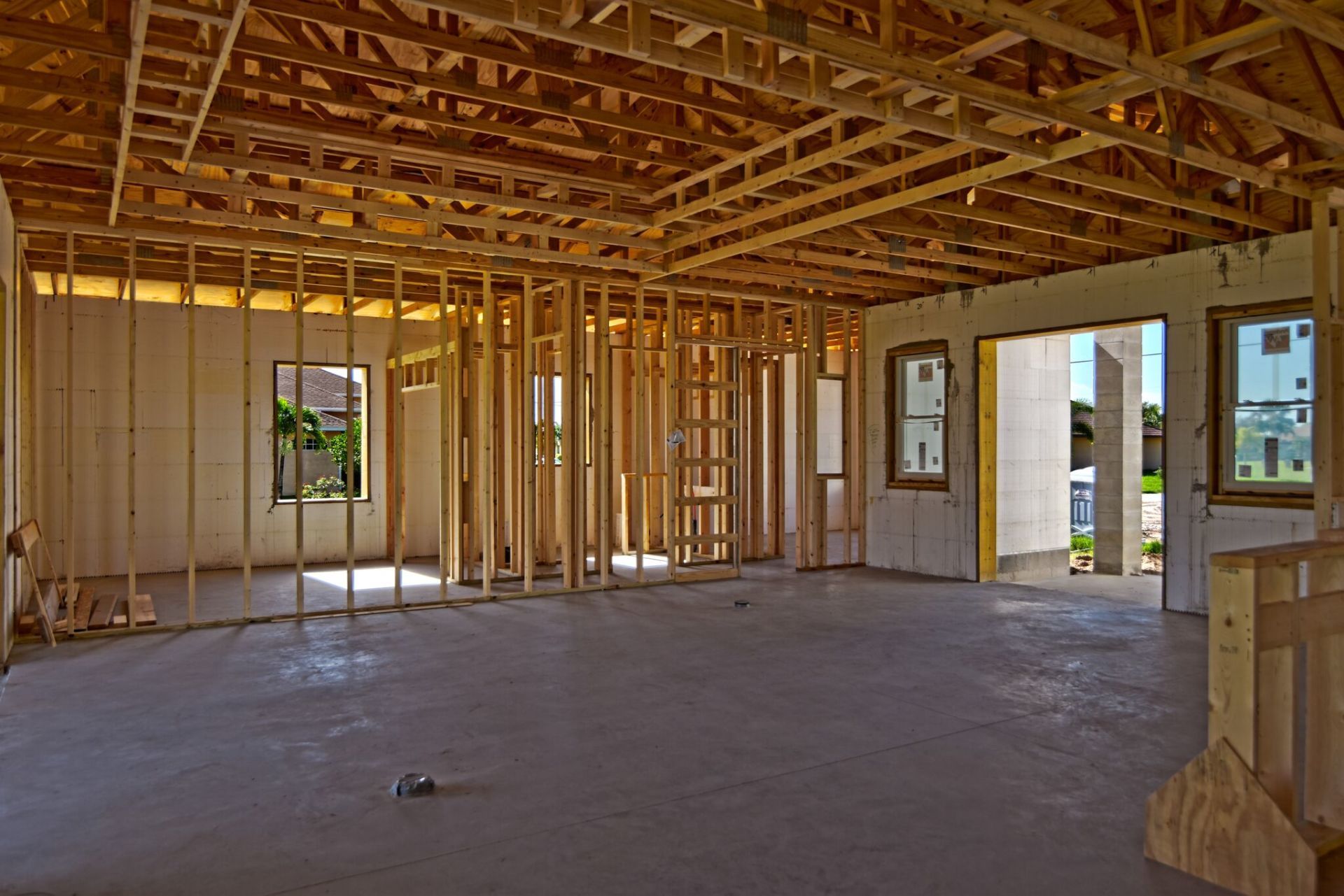 Interior of a building under construction, showing wooden framing for walls, ceiling, and open doorways with concrete floor.