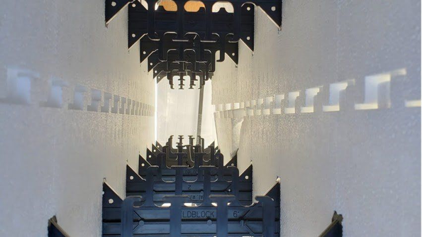 Inside a white tunnel with black, geometric structures on walls.
