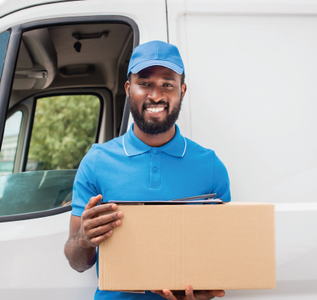 Delivery person holding a box, smiling. Standing in front of a white van, wearing blue cap and shirt.